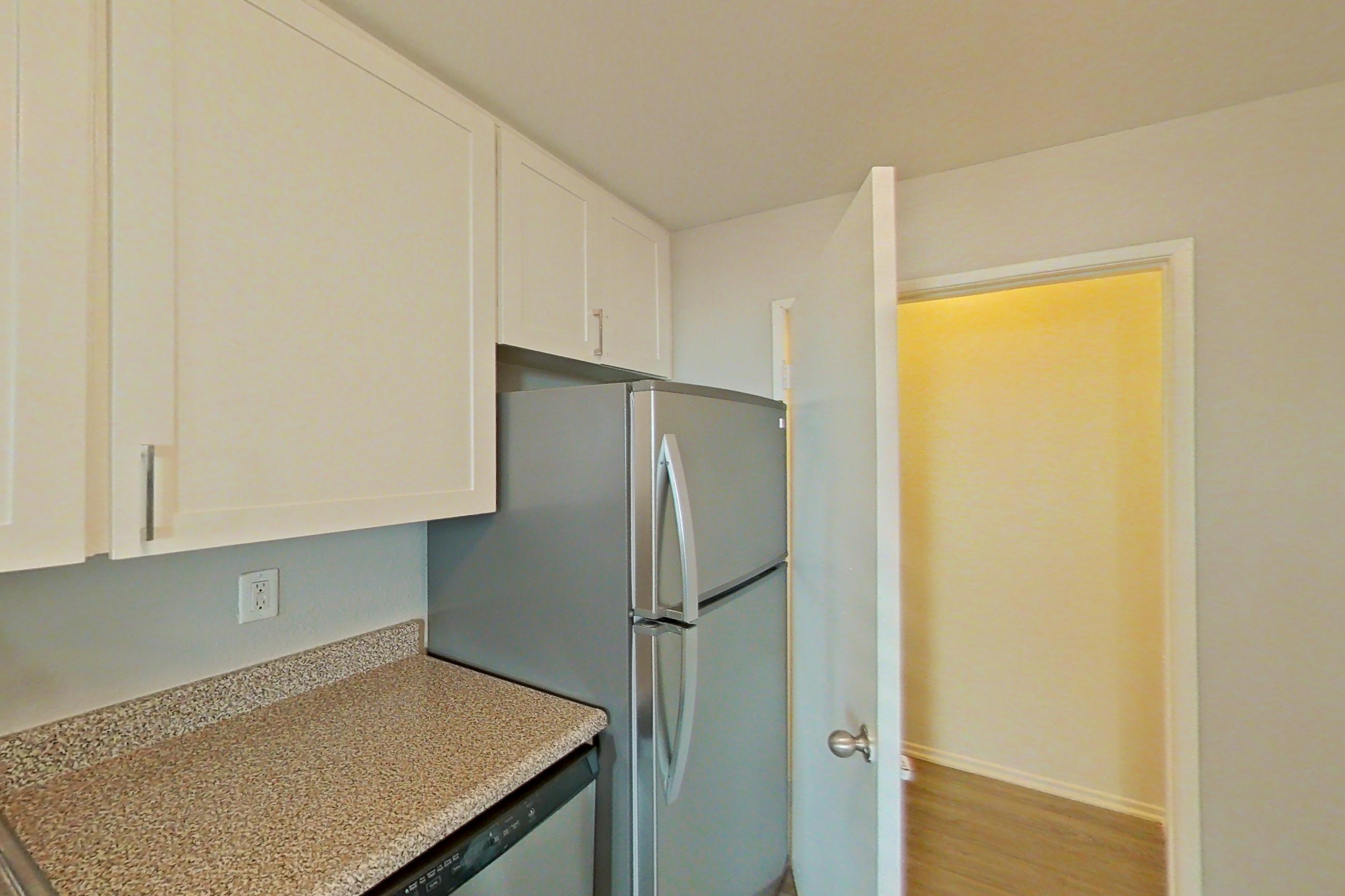 Kitchen with dishwasher, light stone countertops, light wood-finish flooring, refrigerator, and stainless steel appliances, Apartment 01-02 at Avana Rancho Cucamonga