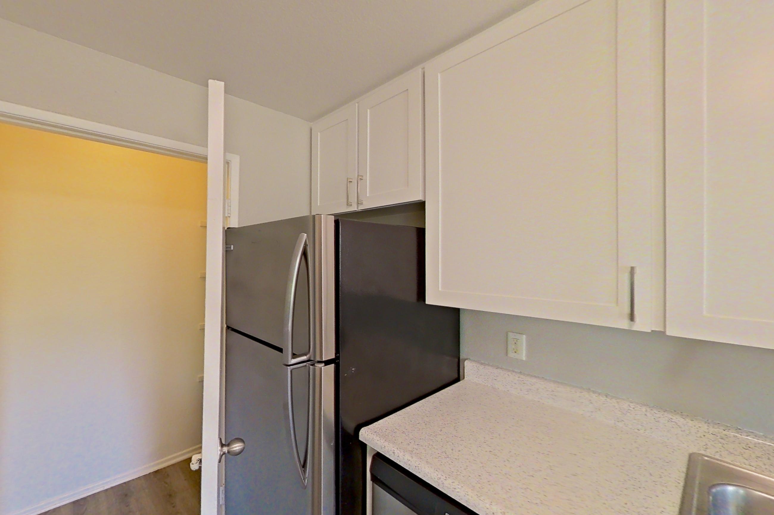 Kitchen with dishwasher, electric range, light stone countertops, light wood-finish flooring, microwave, oven/range, refrigerator, and stainless steel appliances, Apartment 02-07 at Avana Rancho Cucamonga