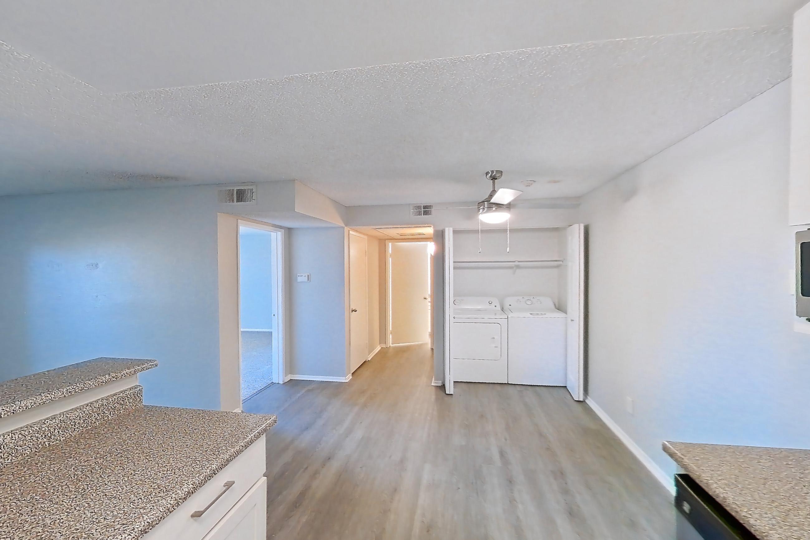 Kitchen with dishwasher, electric range, in-unit laundry, light countertops, light stone countertops, light wood-finish flooring, oven/range, refrigerator, and stainless steel appliances, Apartment 03-09 at Avana Rancho Cucamonga