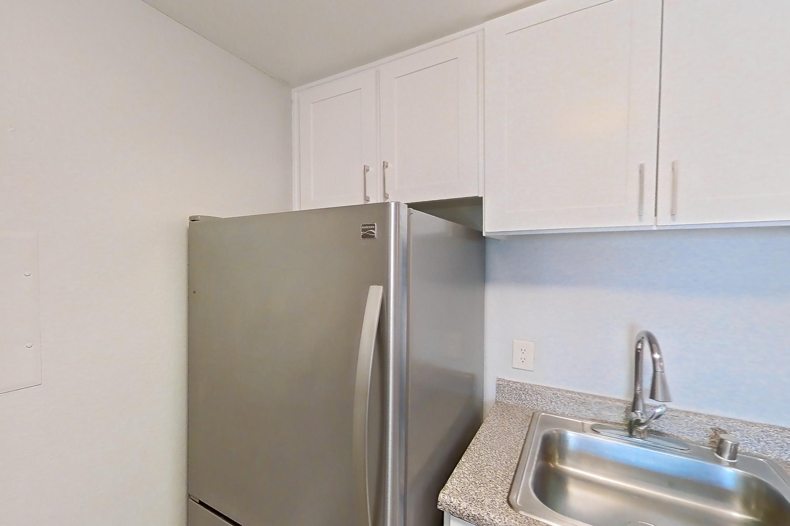 Kitchen with dishwasher, electric range, in-unit laundry, light countertops, light stone countertops, light wood-finish flooring, oven/range, refrigerator, and stainless steel appliances, Apartment 03-10 at Avana Rancho Cucamonga
