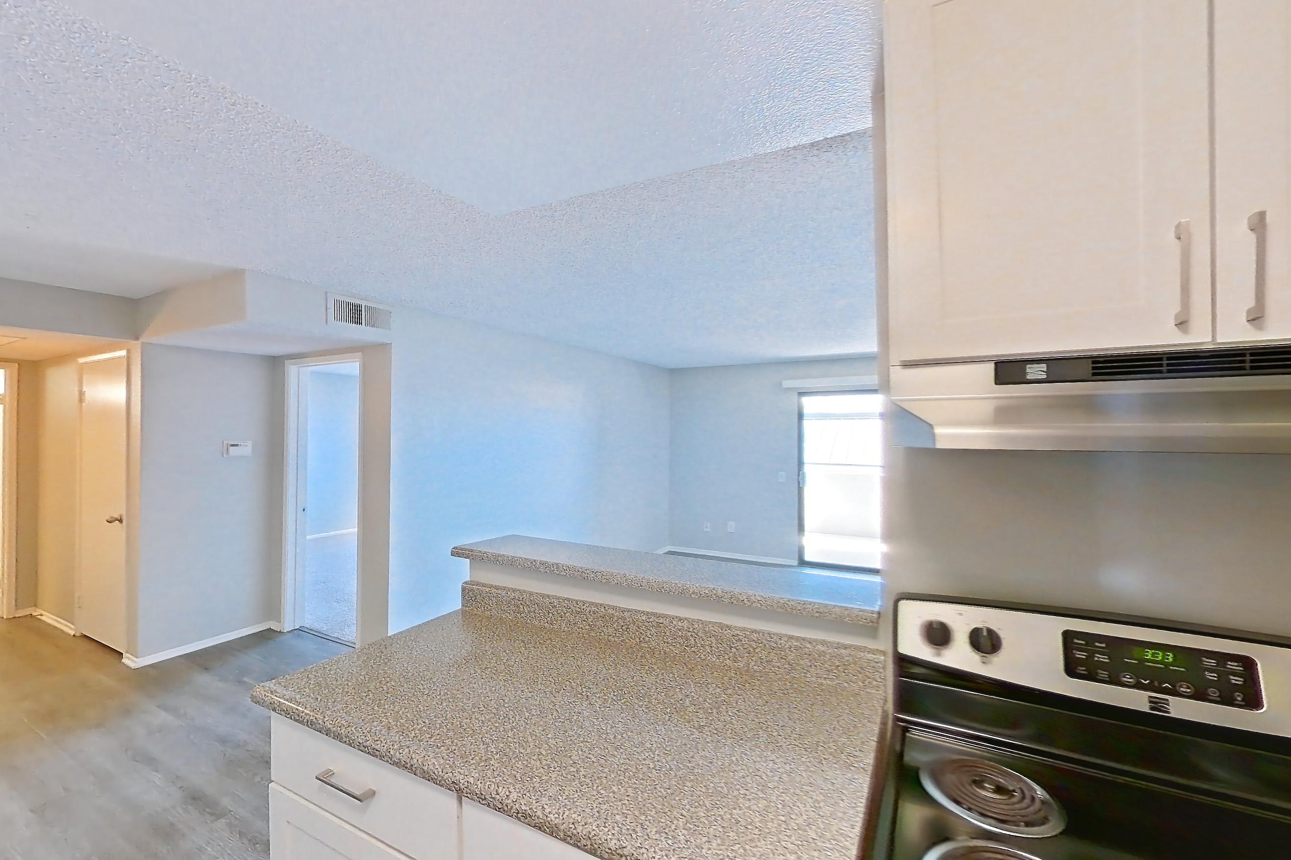 Kitchen with dishwasher, electric range, in-unit laundry, light countertops, light stone countertops, light wood-finish flooring, oven/range, refrigerator, and stainless steel appliances, Apartment 03-10 at Avana Rancho Cucamonga