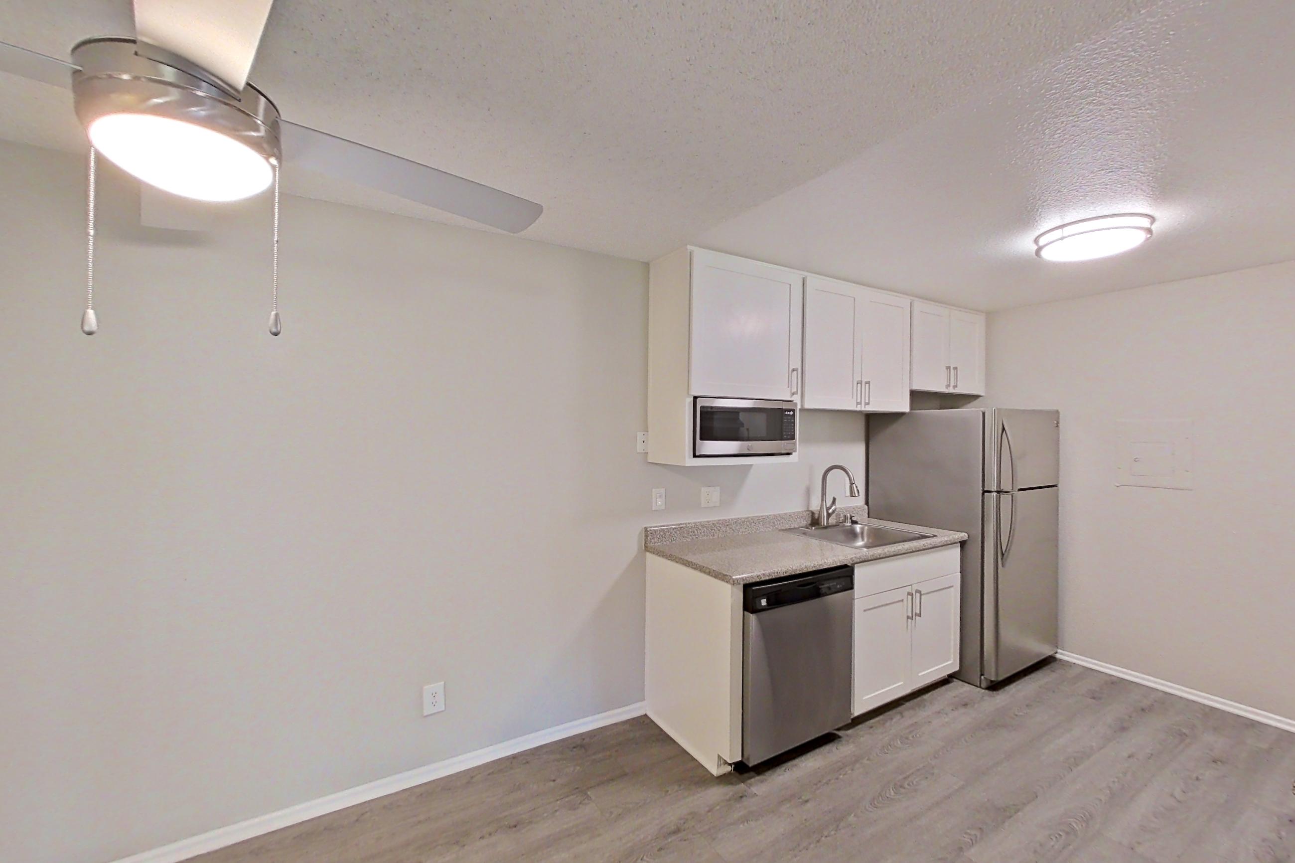 Dining area with dark wood-finish flooring, dishwasher, electric range, in-unit laundry, light countertops, light wood-finish flooring, refrigerator, and stainless steel appliances, Apartment 04-04 at Avana Rancho Cucamonga