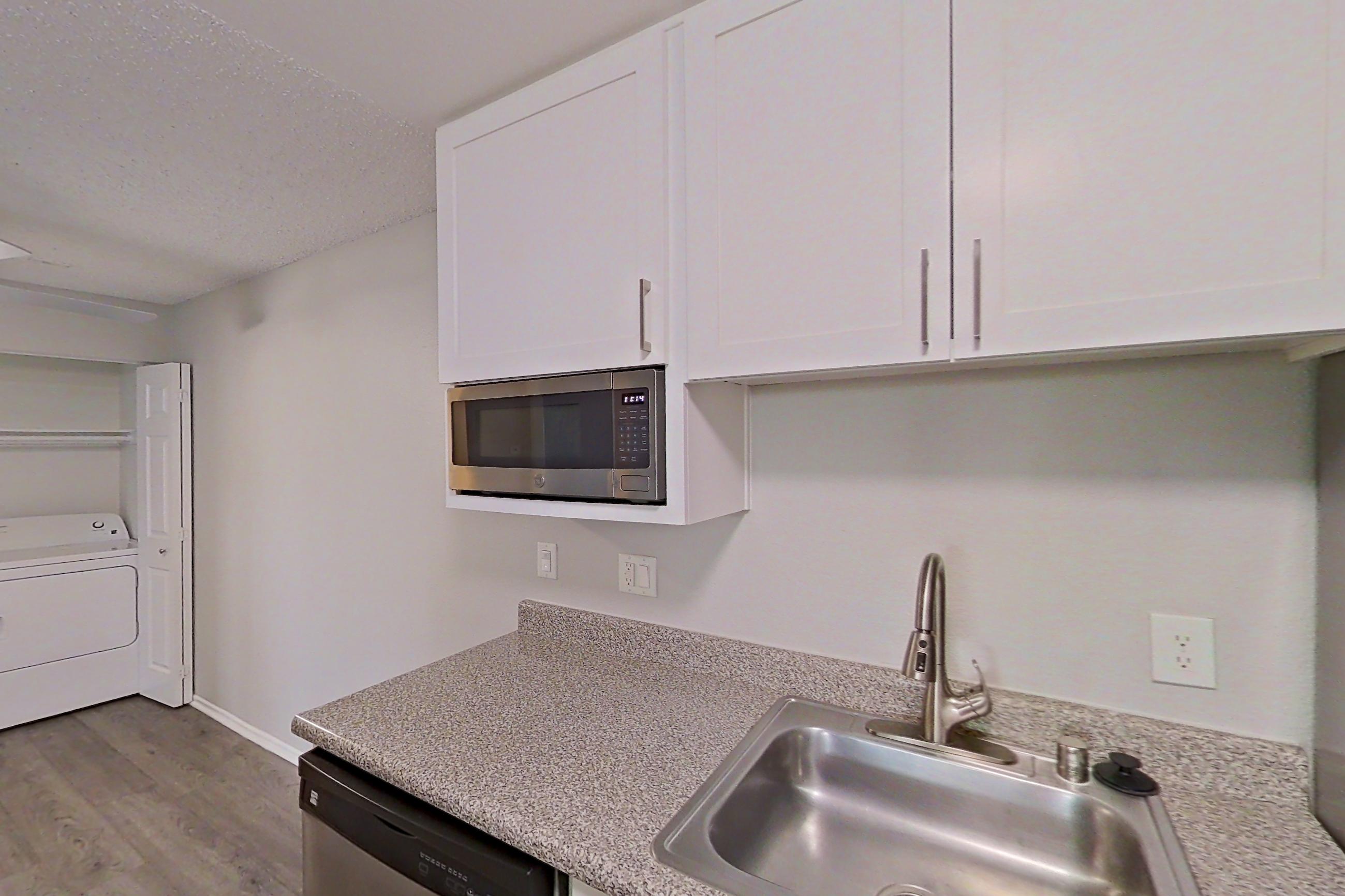 Kitchen with dishwasher, electric range, light countertops, light wood-finish flooring, microwave, oven/range, refrigerator, and stainless steel appliances, Apartment 04-04 at Avana Rancho Cucamonga