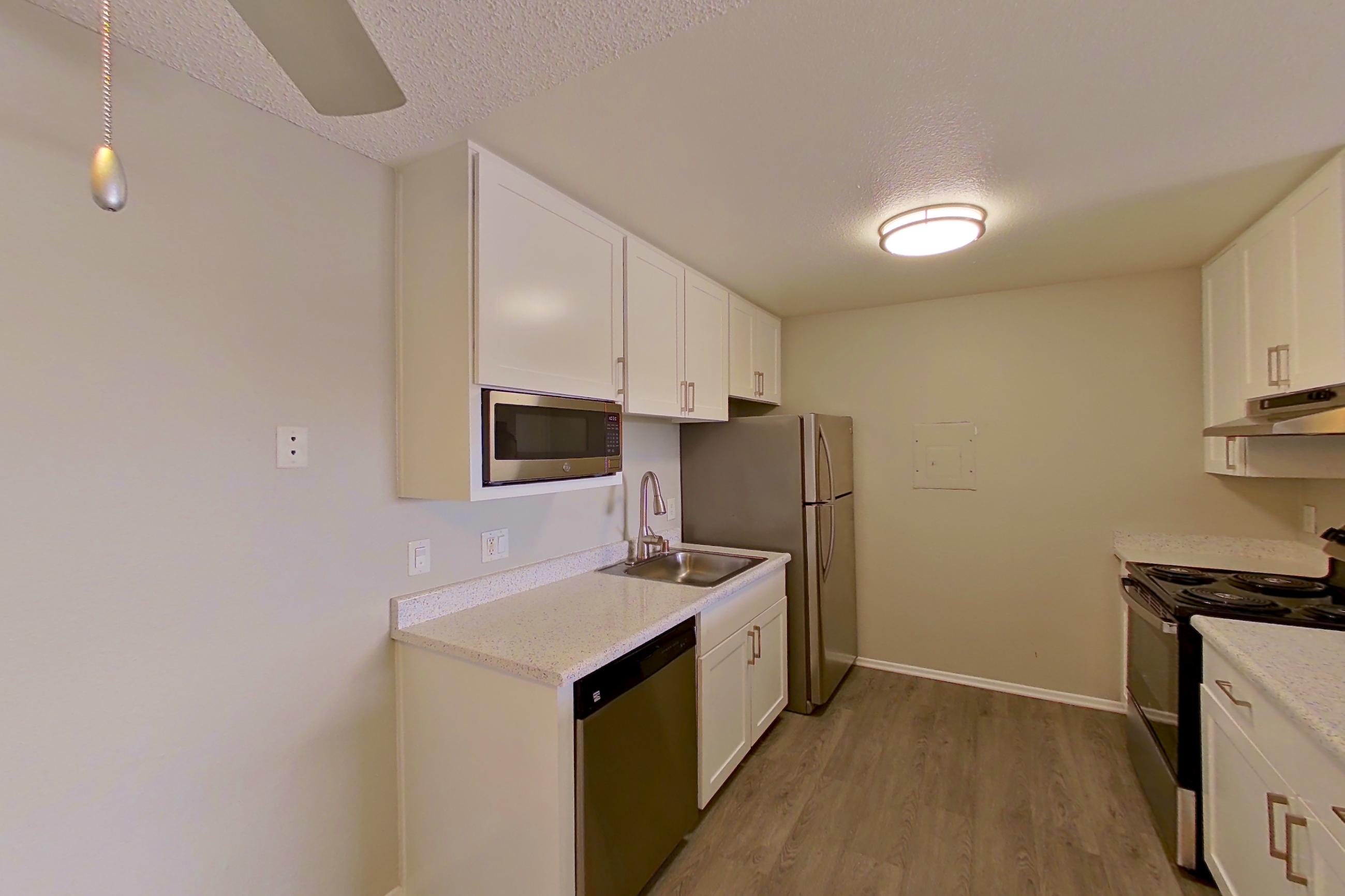 Dining space with dishwasher, electric range, in-unit laundry, light stone countertops, light wood-finish flooring, refrigerator, and stainless steel appliances, Apartment 04-05 at Avana Rancho Cucamonga