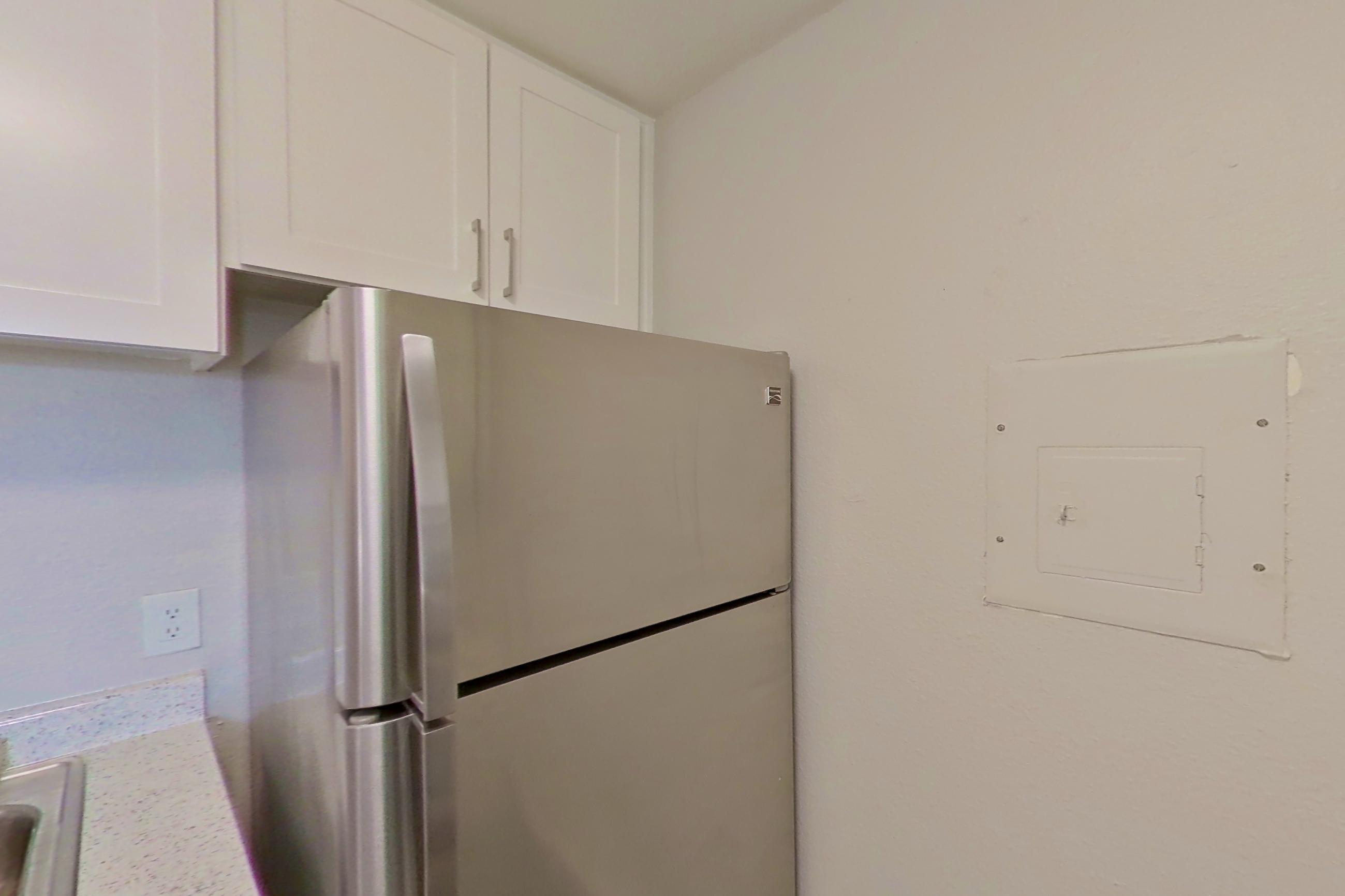 Kitchen with dishwasher, electric range, in-unit laundry, light countertops, light stone countertops, light wood-finish flooring, oven/range, refrigerator, and stainless steel appliances, Apartment 04-05 at Avana Rancho Cucamonga