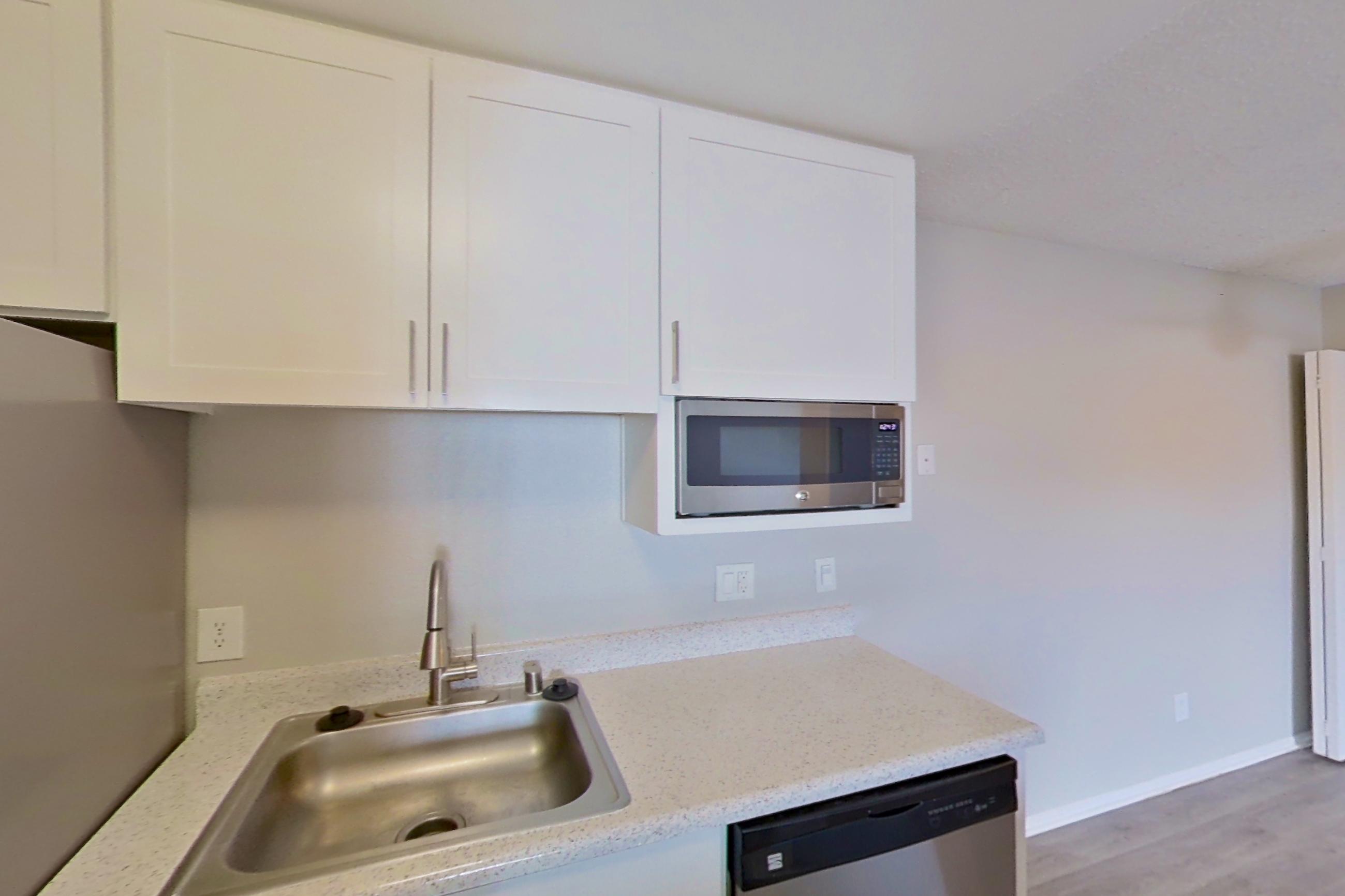 Kitchen with dishwasher, electric range, light stone countertops, light wood-finish flooring, oven/range, refrigerator, and stainless steel appliances, Apartment 04-07 at Avana Rancho Cucamonga