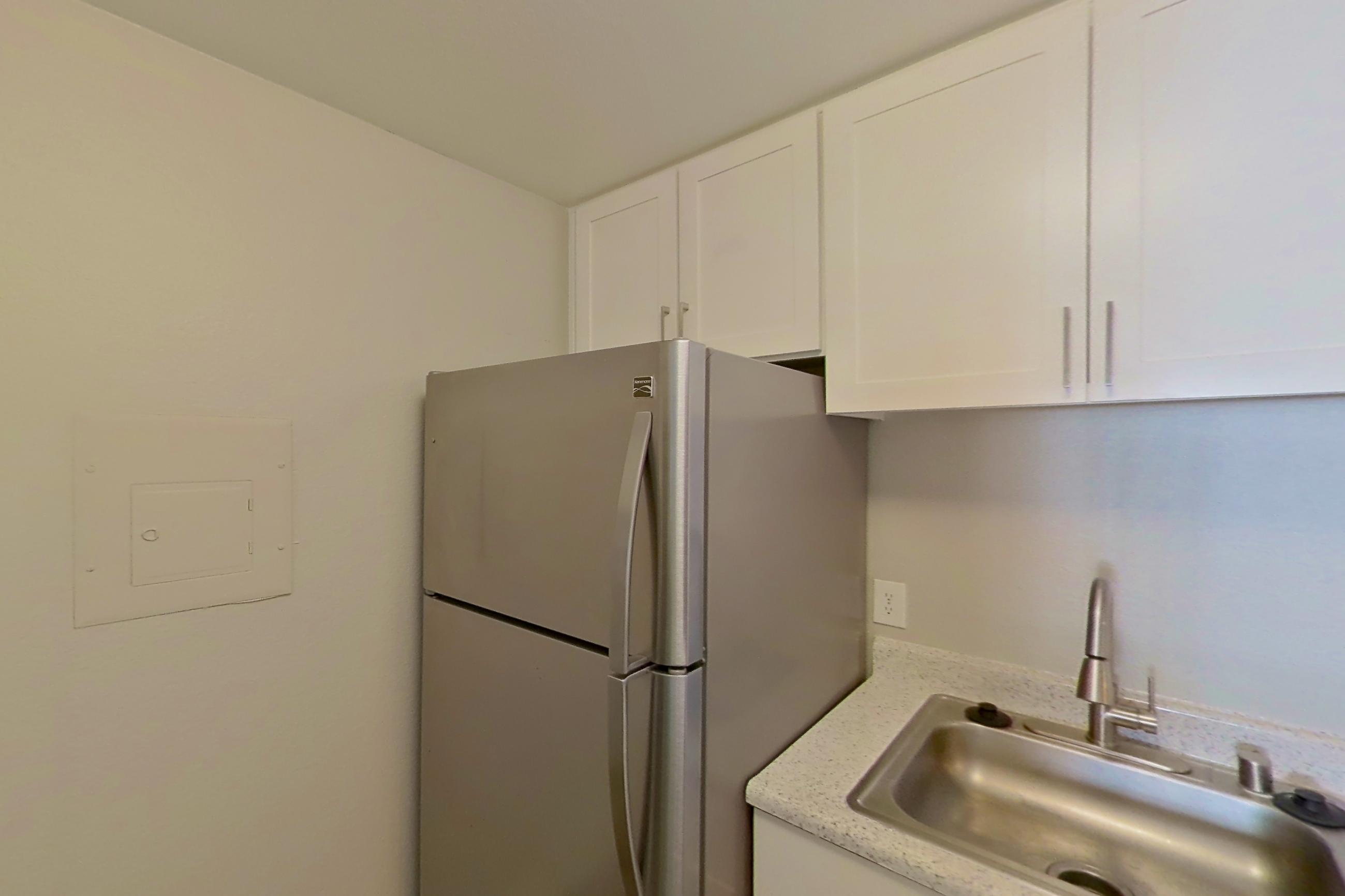 Kitchen with dishwasher, electric range, light stone countertops, light wood-finish flooring, oven/range, refrigerator, and stainless steel appliances, Apartment 04-07 at Avana Rancho Cucamonga