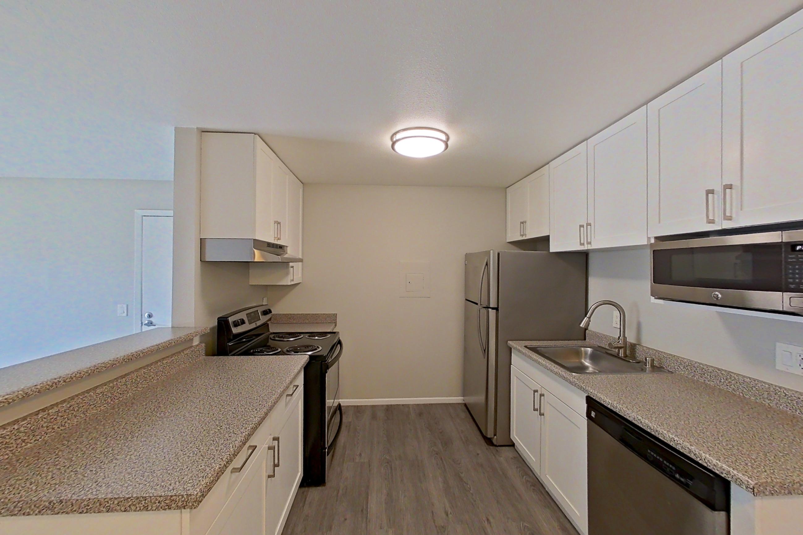 Dining area with dishwasher, electric range, in-unit laundry, light countertops, light wood-finish flooring, refrigerator, and stainless steel appliances, Apartment 05-03 at Avana Rancho Cucamonga