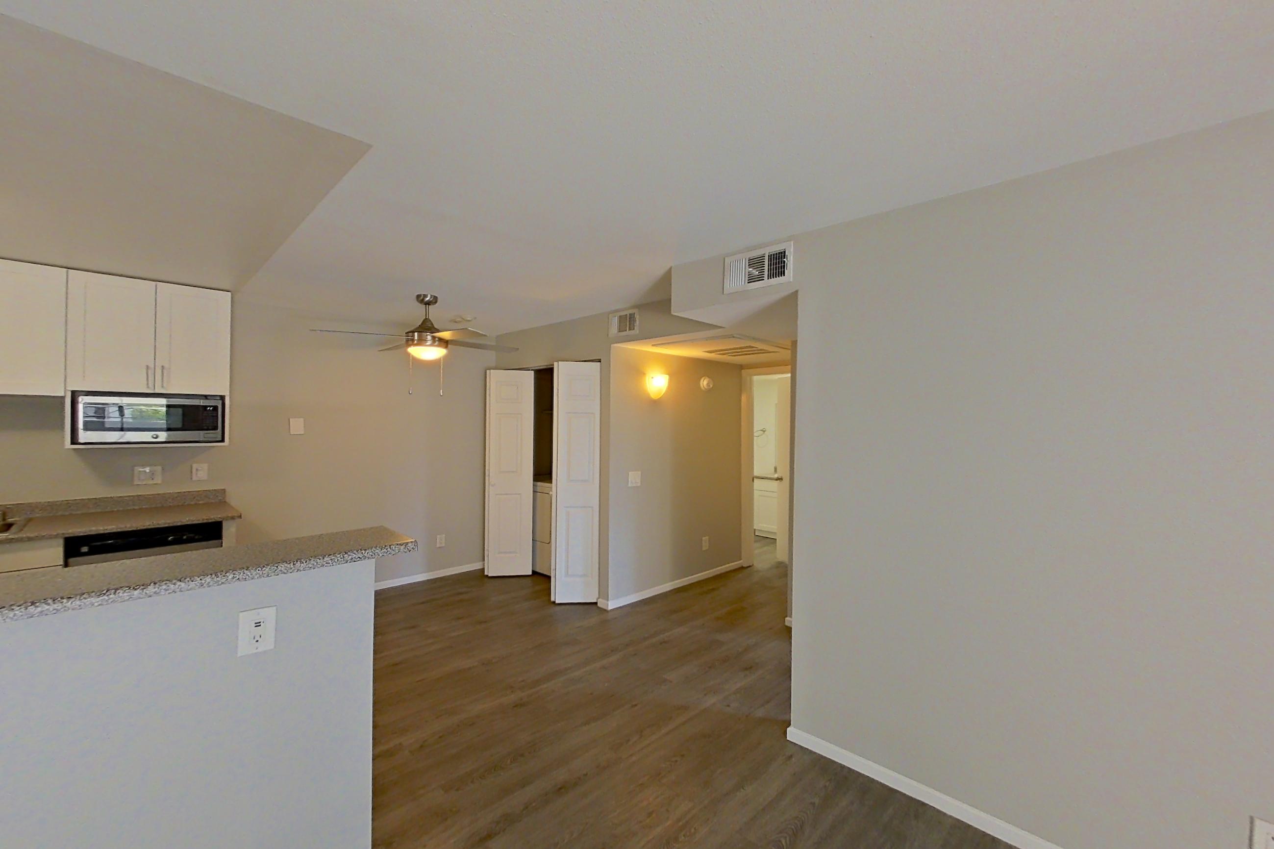 Living room with dark wood-finish flooring, light countertops, refrigerator, and stainless steel appliances, Apartment 05-03 at Avana Rancho Cucamonga