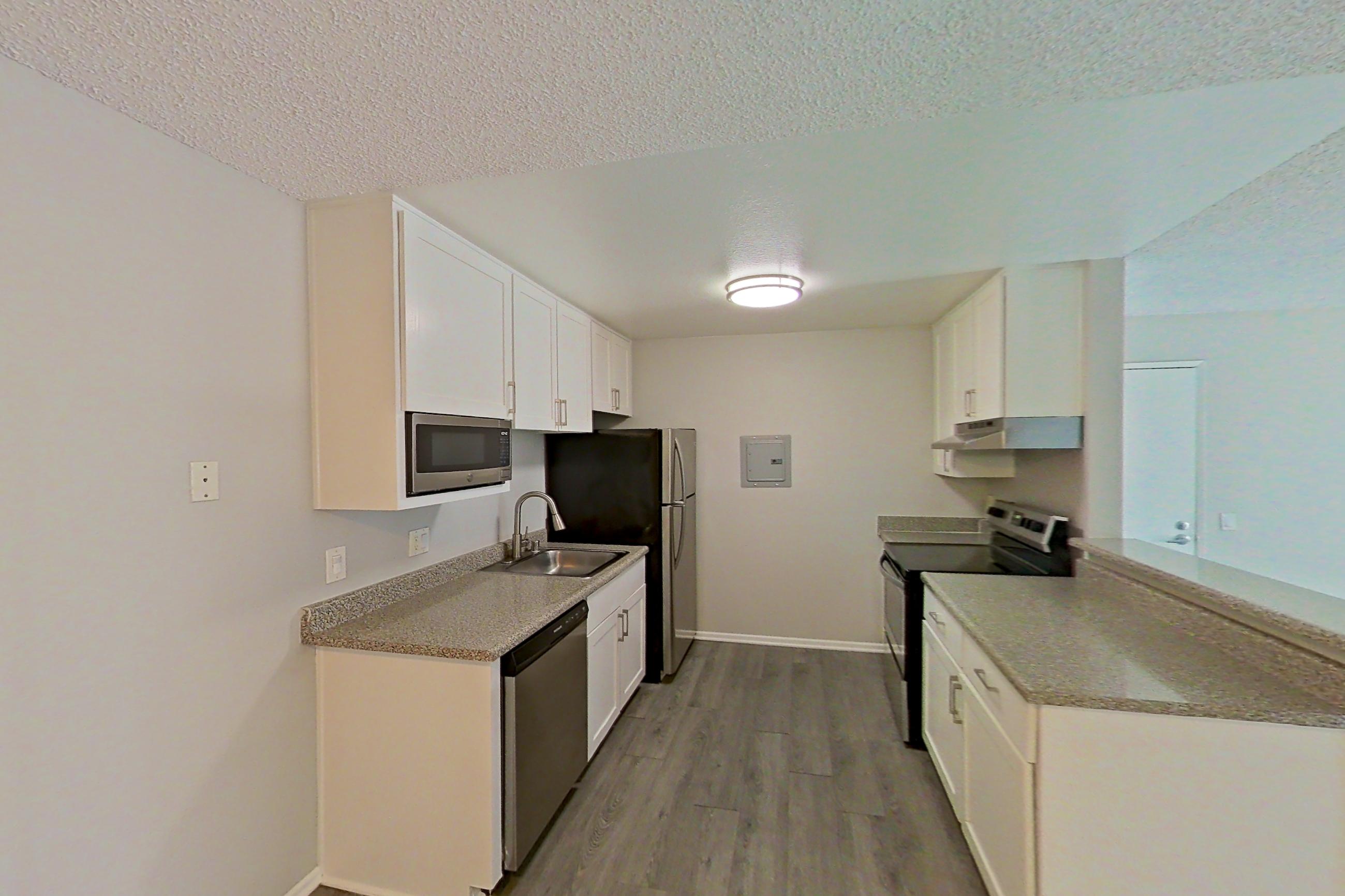 Dining area with electric range, in-unit laundry, light stone countertops, light wood-finish flooring, oven/range, refrigerator, and stainless steel appliances, Apartment 05-05 at Avana Rancho Cucamonga