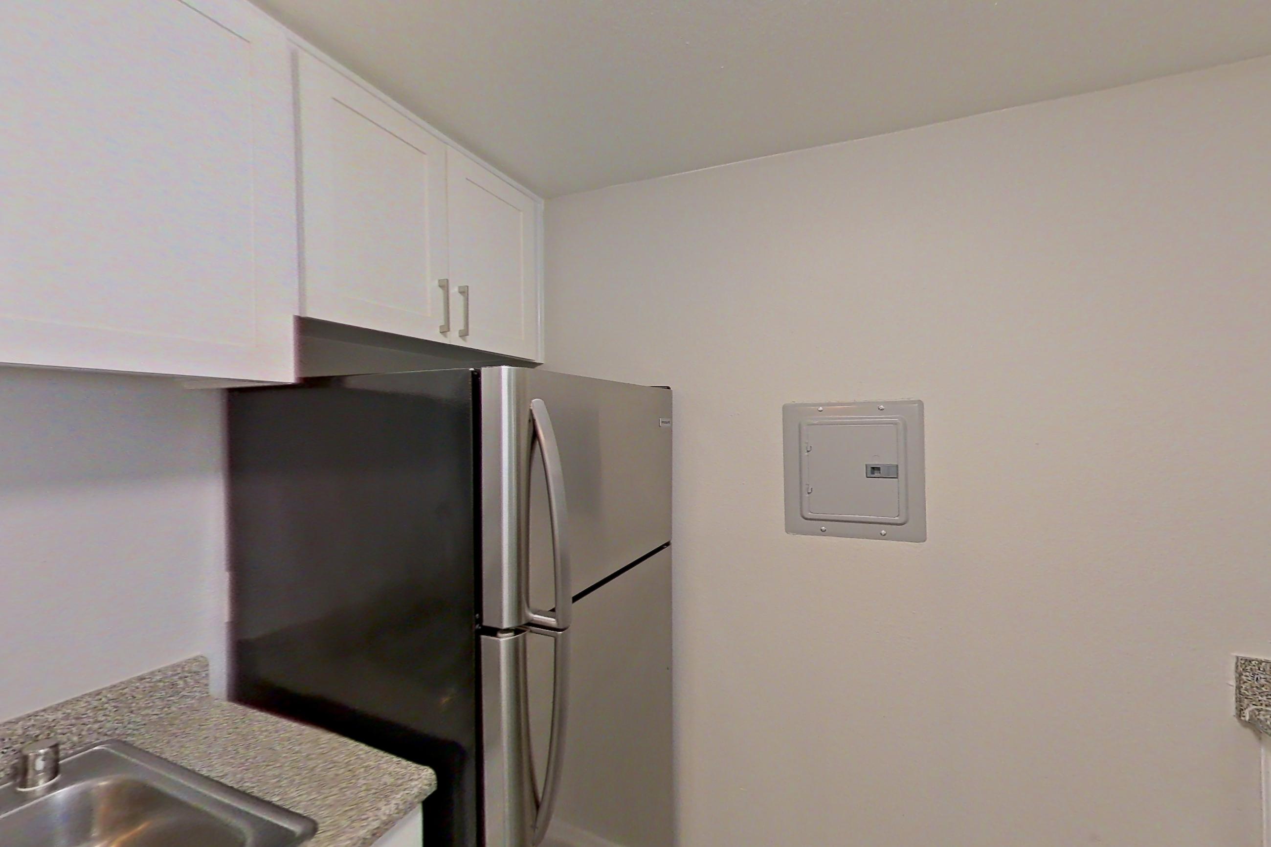 Kitchen with dishwasher, in-unit laundry, light countertops, light stone countertops, light wood-finish flooring, microwave, oven/range, refrigerator, and stainless steel appliances, Apartment 05-05 at Avana Rancho Cucamonga