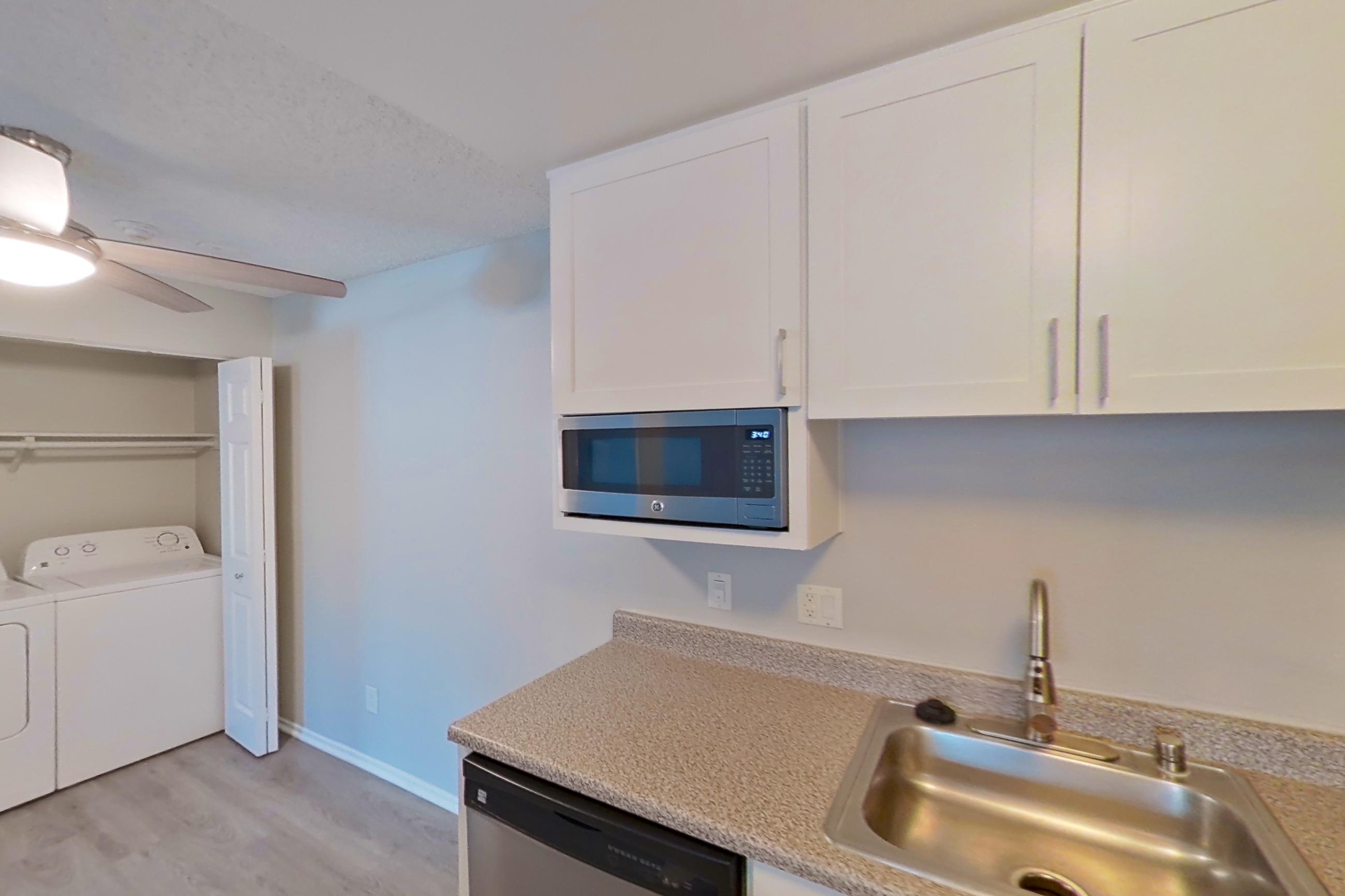 Kitchen with dishwasher, electric range, light countertops, light stone countertops, light wood-finish flooring, microwave, oven/range, refrigerator, and stainless steel appliances, Apartment 05-08 at Avana Rancho Cucamonga