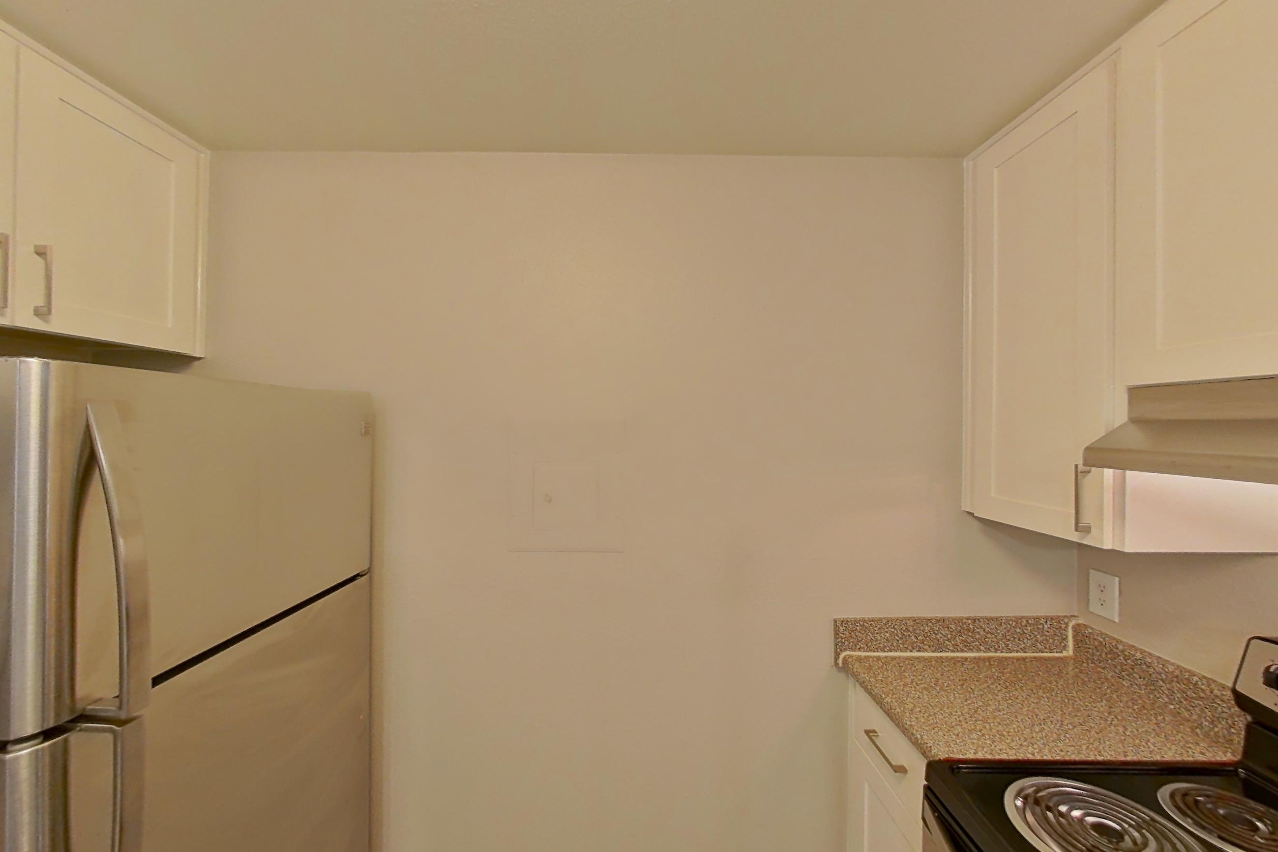 Kitchen with dishwasher, electric range, light countertops, light stone countertops, light wood-finish flooring, microwave, oven/range, refrigerator, and stainless steel appliances, Apartment 05-08 at Avana Rancho Cucamonga
