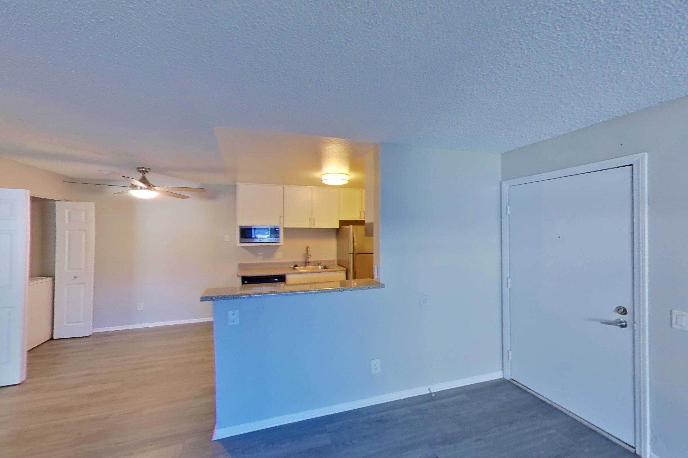 Living space with dark wood-finish flooring, light countertops, and refrigerator, Apartment 05-08 at Avana Rancho Cucamonga