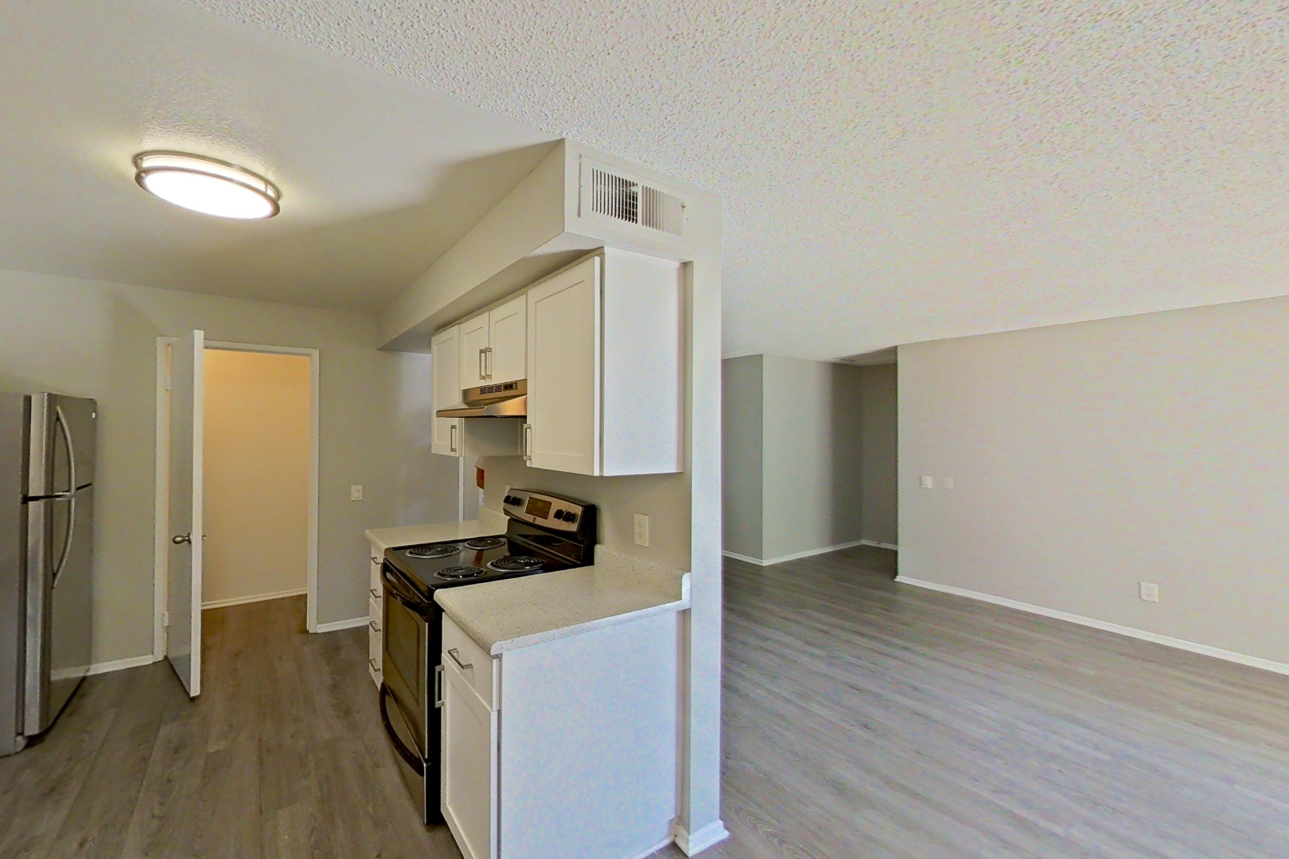 Dining area with dishwasher, electric range, light countertops, light stone countertops, light wood-finish flooring, refrigerator, and stainless steel appliances, Apartment 06-05 at Avana Rancho Cucamonga