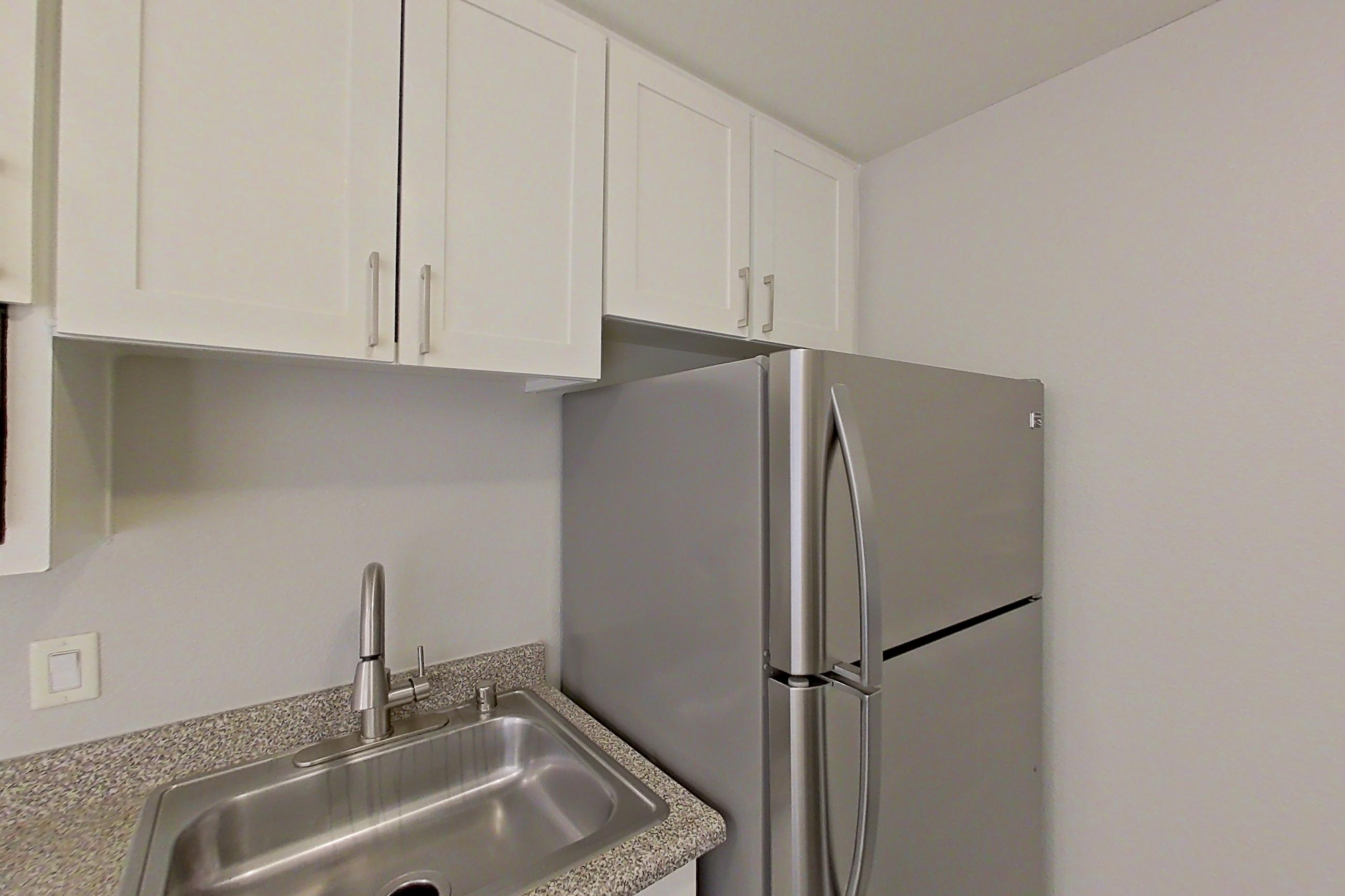 Kitchen with dishwasher, electric range, light countertops, light wood-finish flooring, microwave, oven/range, refrigerator, and stainless steel appliances, Apartment 06-06 at Avana Rancho Cucamonga
