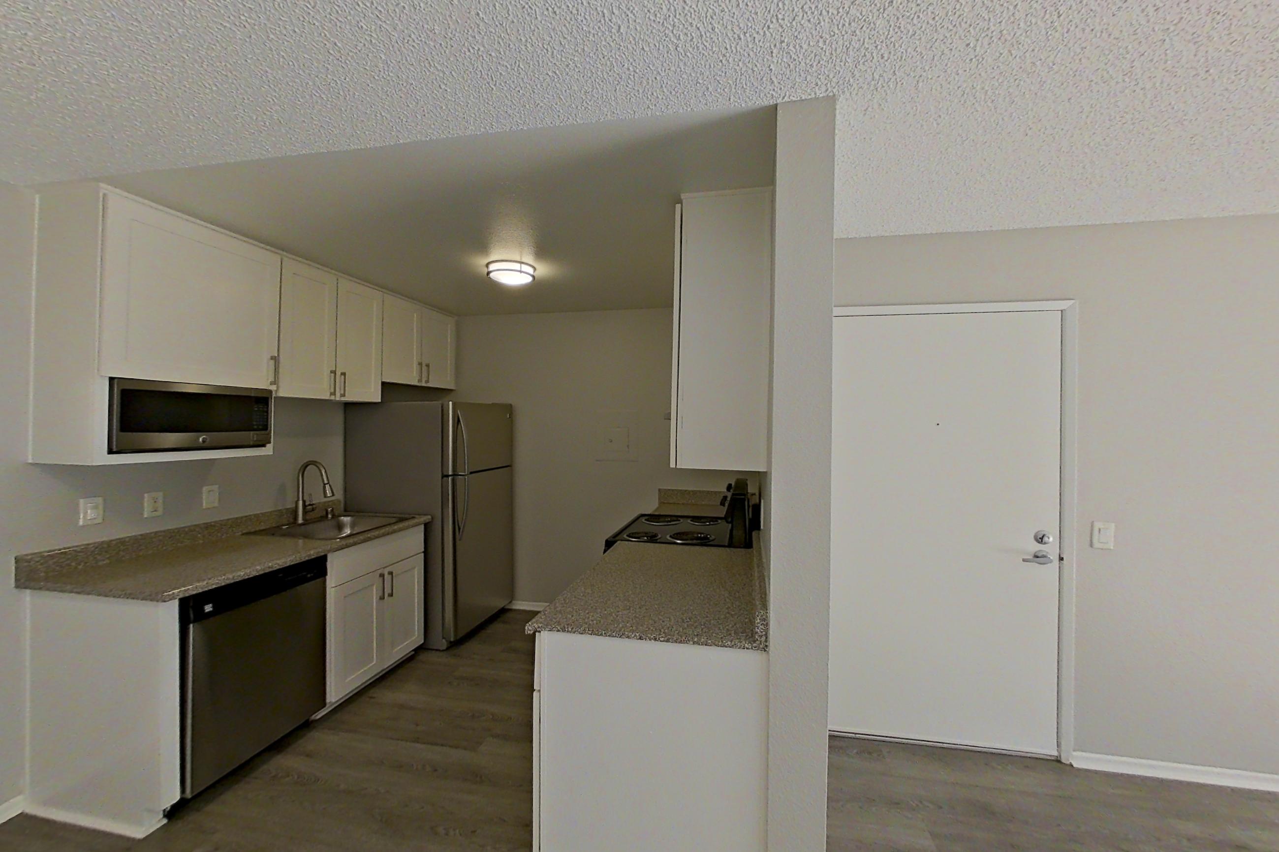 Living room with dishwasher, light stone countertops, refrigerator, stainless steel appliances, and white appliances, Apartment 06-06 at Avana Rancho Cucamonga