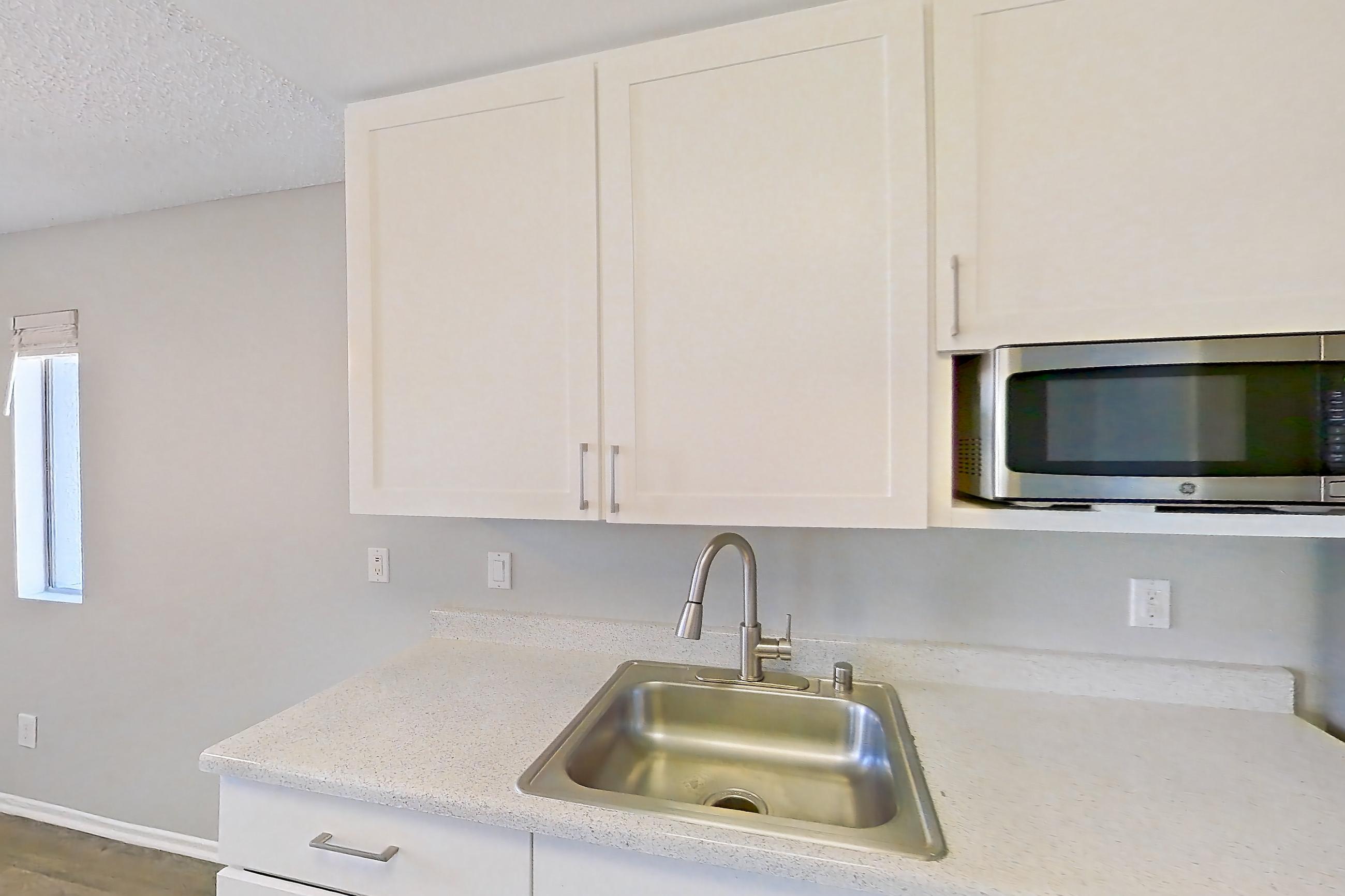 Kitchen with dishwasher, electric range, light countertops, light stone countertops, light wood-finish flooring, microwave, oven/range, range hood, and stainless steel appliances, Apartment 07-01 at Avana Rancho Cucamonga