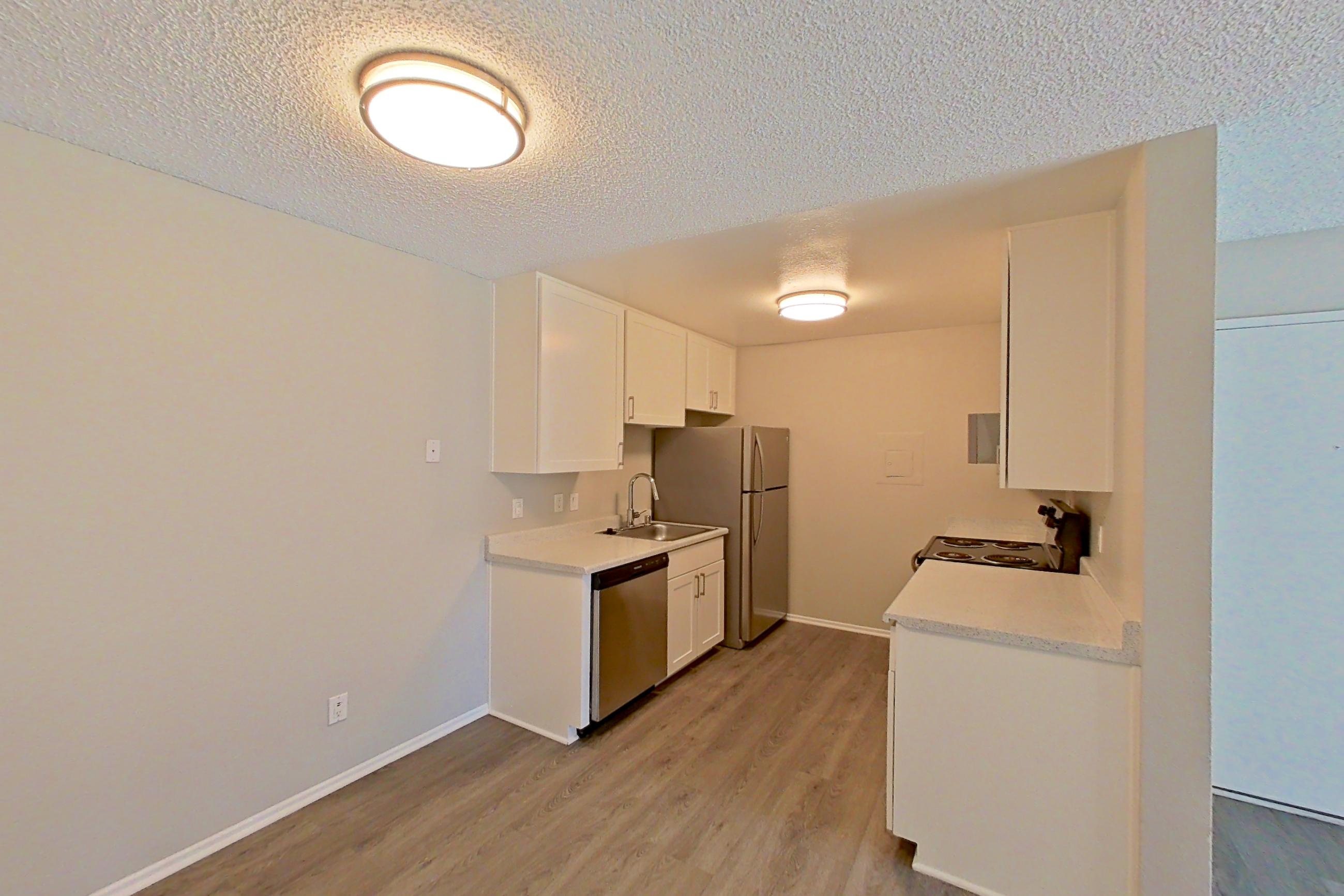 Dining area with dishwasher, light countertops, light wood-finish flooring, refrigerator, stainless steel appliances, and white appliances, Apartment 07-06 at Avana Rancho Cucamonga