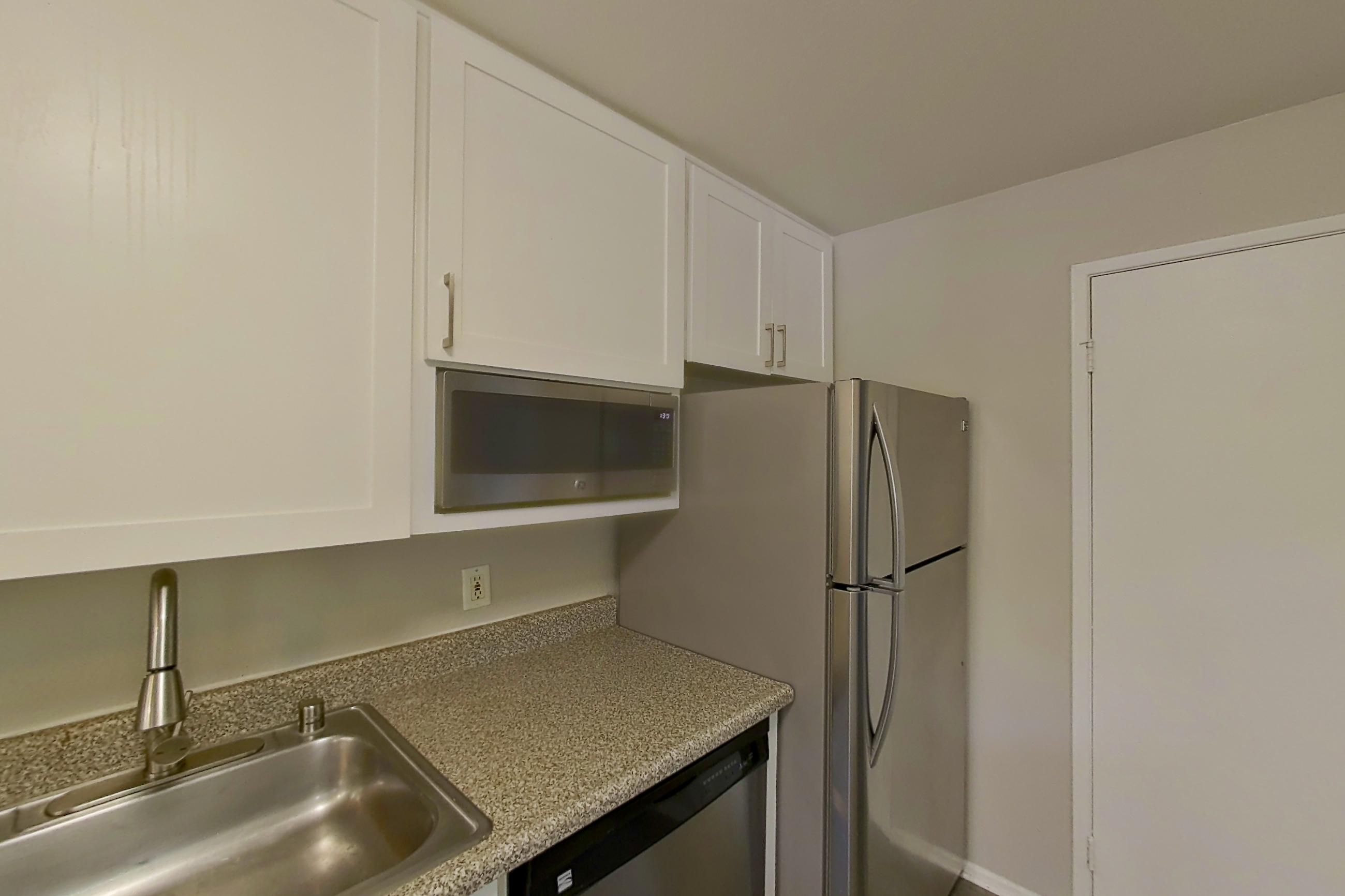 Kitchen with dark wood-finish flooring, dishwasher, electric range, light countertops, oven/range, refrigerator, and stainless steel appliances, Apartment 08-01 at Avana Rancho Cucamonga
