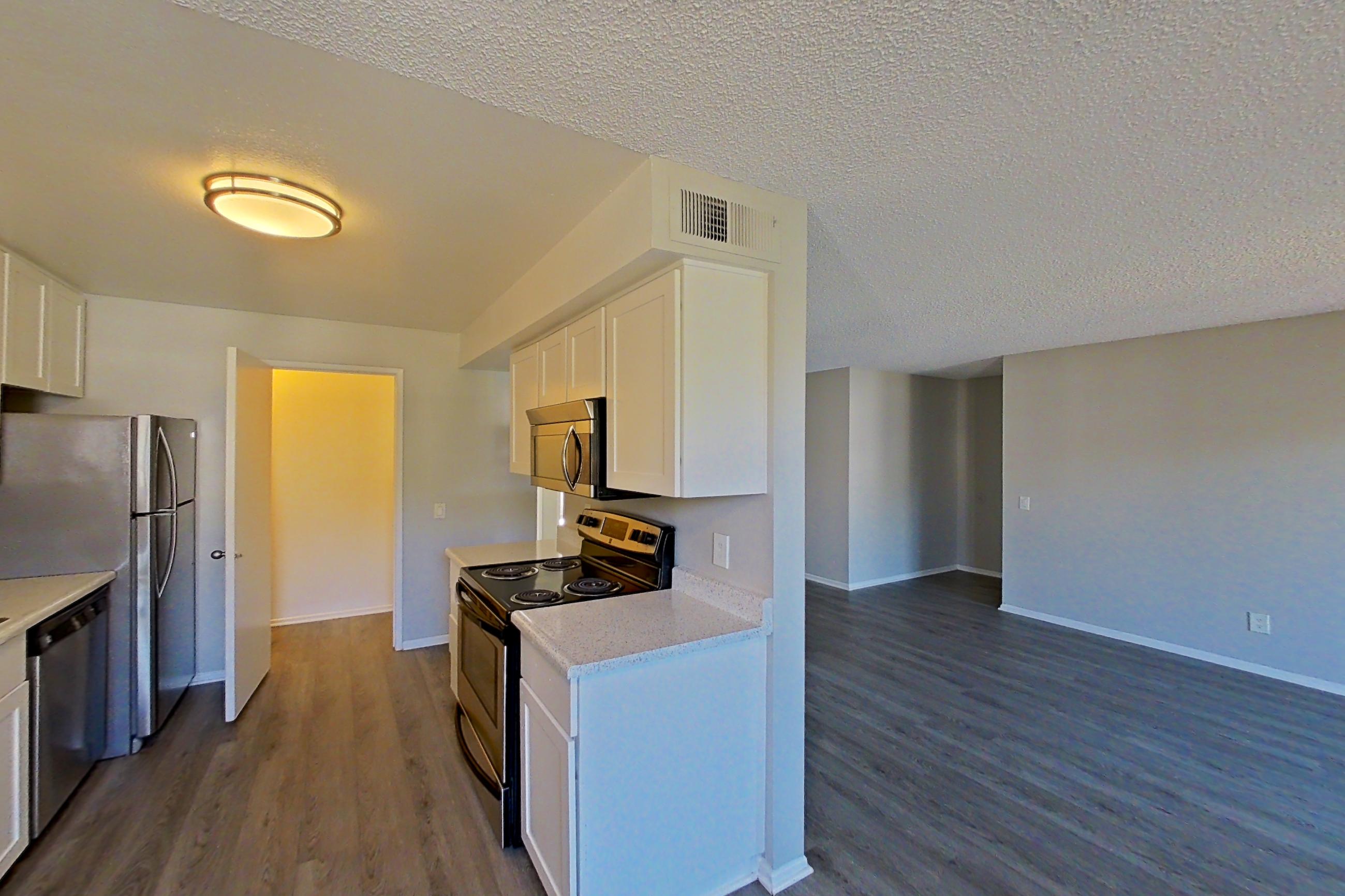 Dining room with dark wood-finish flooring, dishwasher, electric range, light countertops, oven/range, and stainless steel appliances, Apartment 09-01 at Avana Rancho Cucamonga