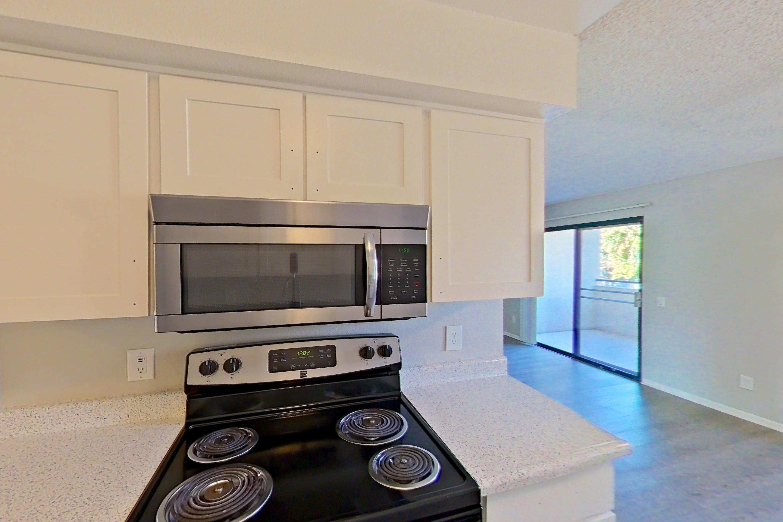Kitchen with dishwasher, electric range, light stone countertops, light wood-finish flooring, microwave, oven/range, refrigerator, and stainless steel appliances, Apartment 09-01 at Avana Rancho Cucamonga