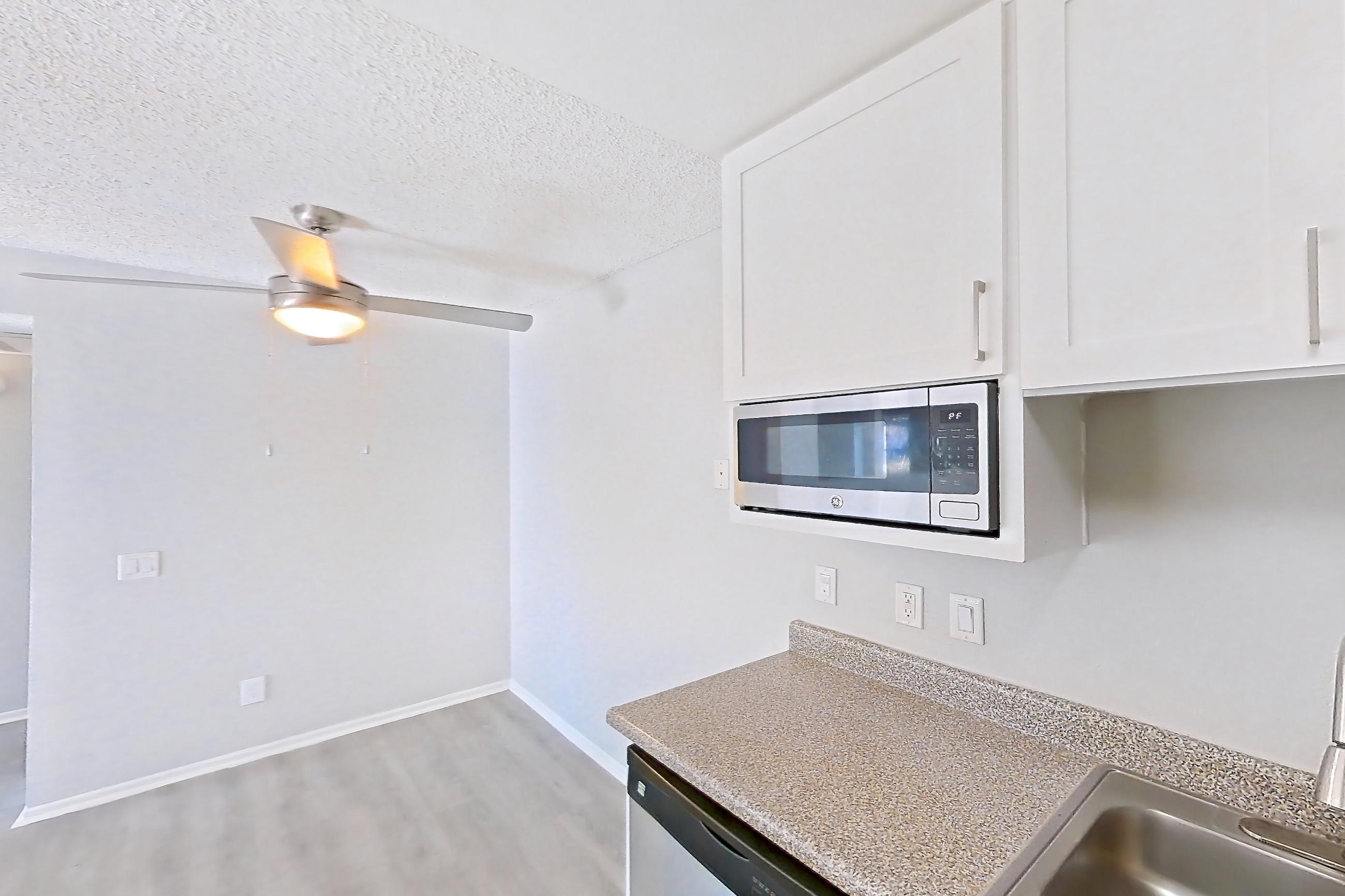Kitchen with dishwasher, electric range, light countertops, light stone countertops, light wood-finish flooring, oven/range, refrigerator, and stainless steel appliances, Apartment 10-02 at Avana Rancho Cucamonga