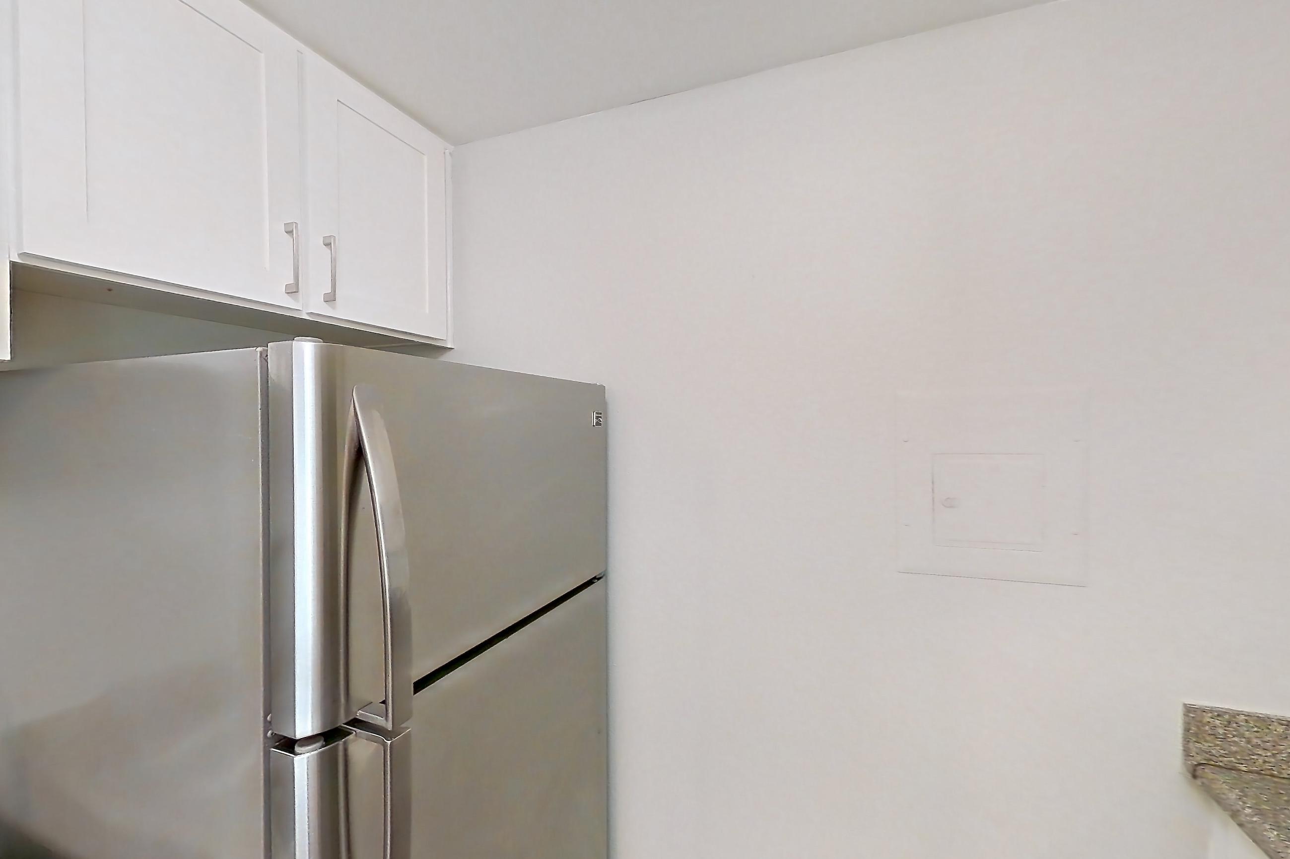 Kitchen with dishwasher, electric range, light countertops, light stone countertops, light wood-finish flooring, oven/range, refrigerator, and stainless steel appliances, Apartment 10-02 at Avana Rancho Cucamonga