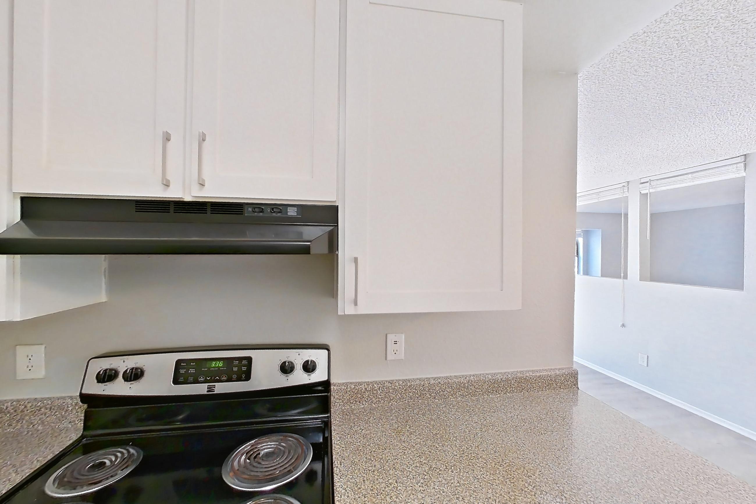 Kitchen with dishwasher, electric range, light countertops, light stone countertops, light wood-finish flooring, oven/range, refrigerator, and stainless steel appliances, Apartment 10-02 at Avana Rancho Cucamonga
