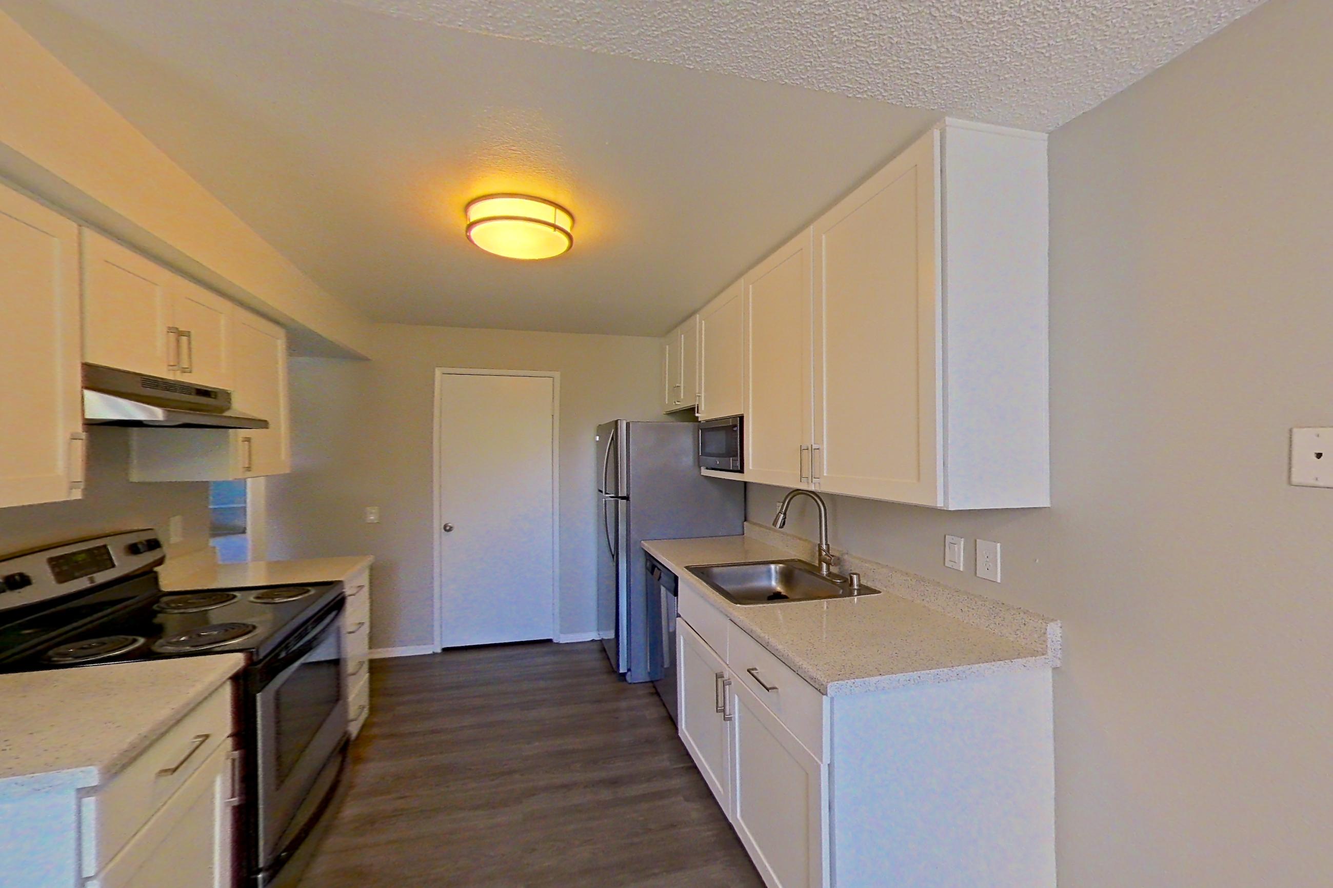 Dining area with dark wood-finish flooring, electric range, light stone countertops, oven/range, refrigerator, stainless steel appliances, and white appliances, Apartment 10-03 at Avana Rancho Cucamonga