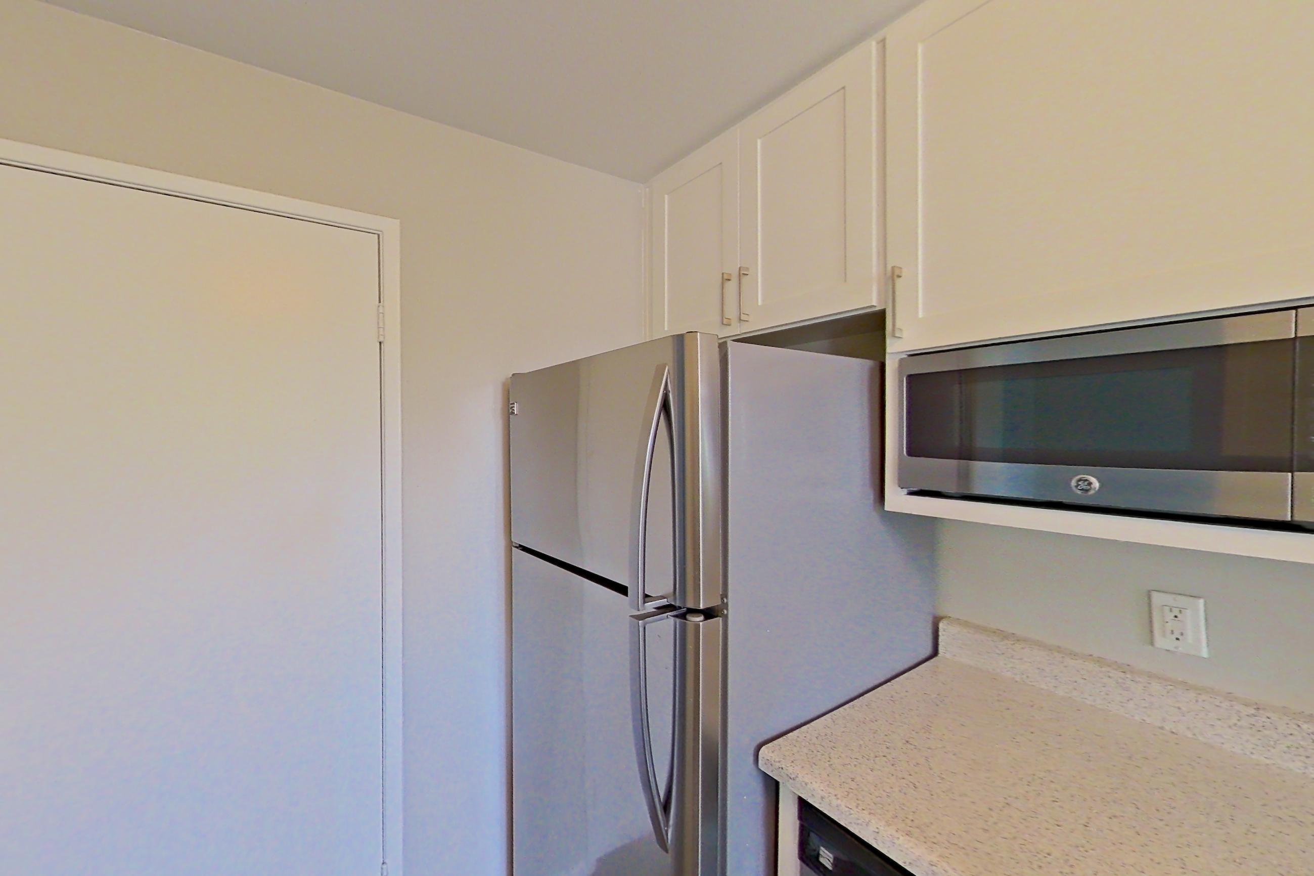Kitchen with dishwasher, electric range, light stone countertops, microwave, oven/range, range hood, refrigerator, and stainless steel appliances, Apartment 10-03 at Avana Rancho Cucamonga