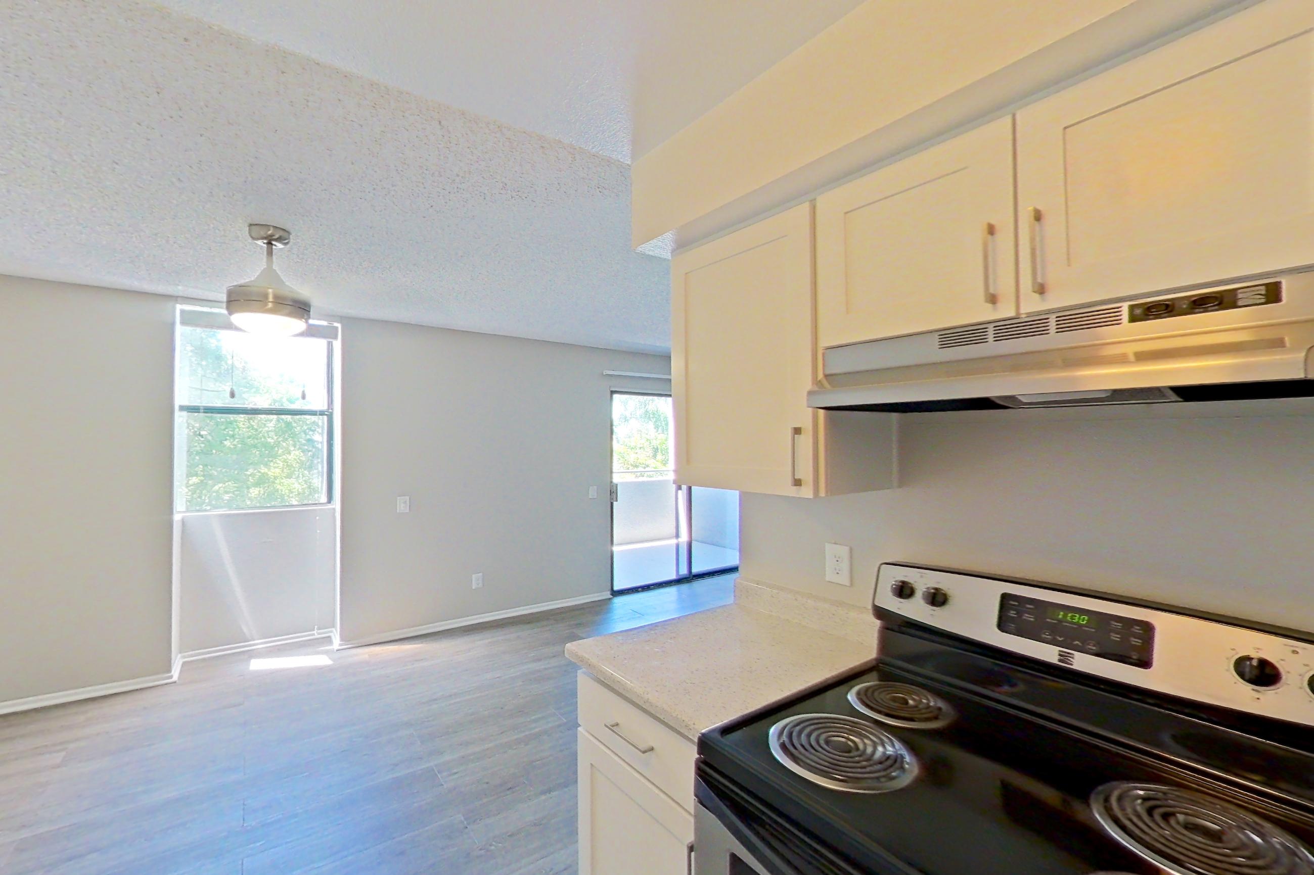 Kitchen with dishwasher, electric range, light stone countertops, microwave, oven/range, range hood, refrigerator, and stainless steel appliances, Apartment 10-03 at Avana Rancho Cucamonga
