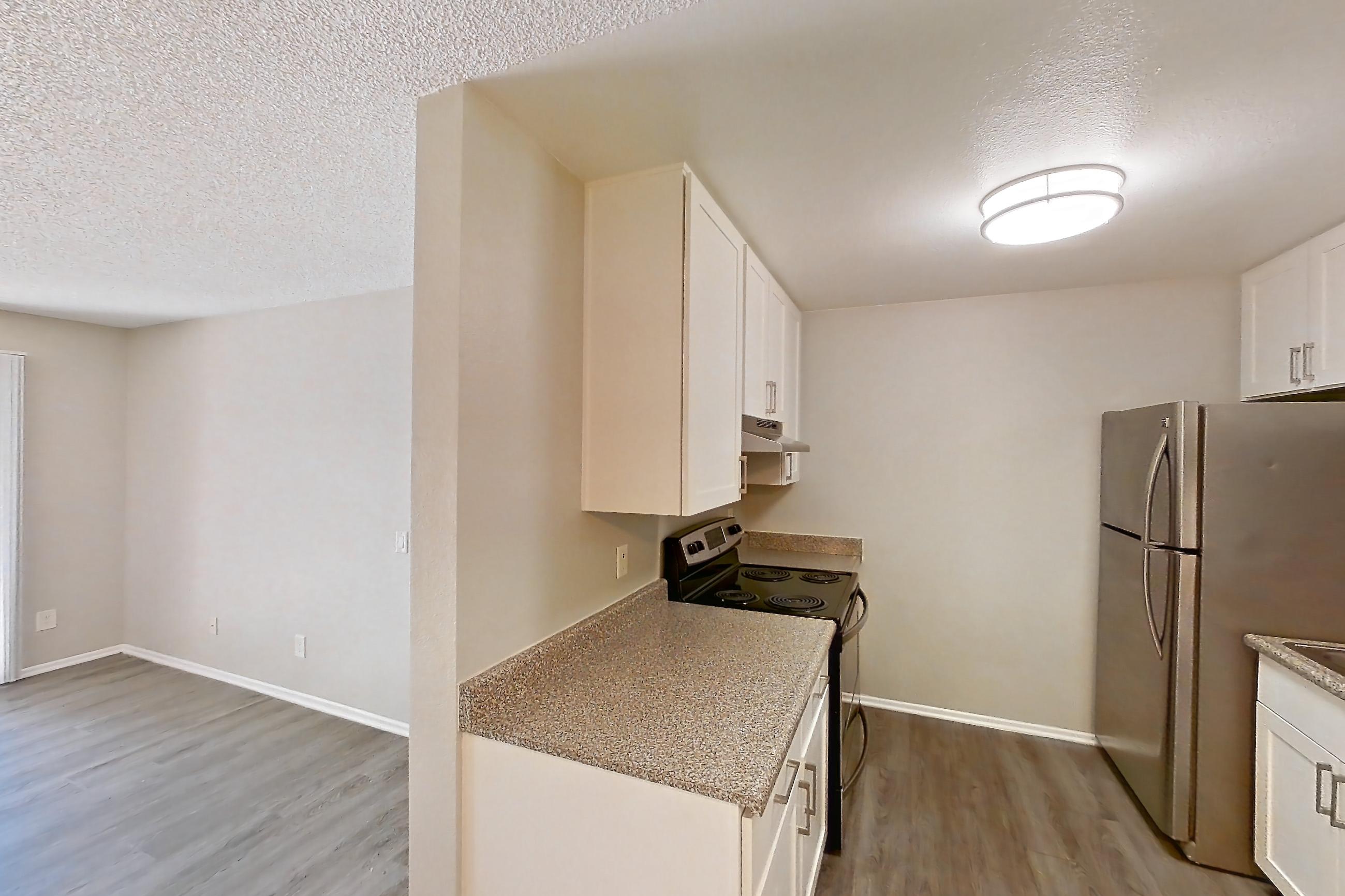 Dining room with black appliances, dark wood-finish flooring, dishwasher, electric range, light carpet, light countertops, light stone countertops, light wood-finish flooring, oven/range, refrigerator, and stainless steel appliances, Apartment 10-04 at Avana Rancho Cucamonga