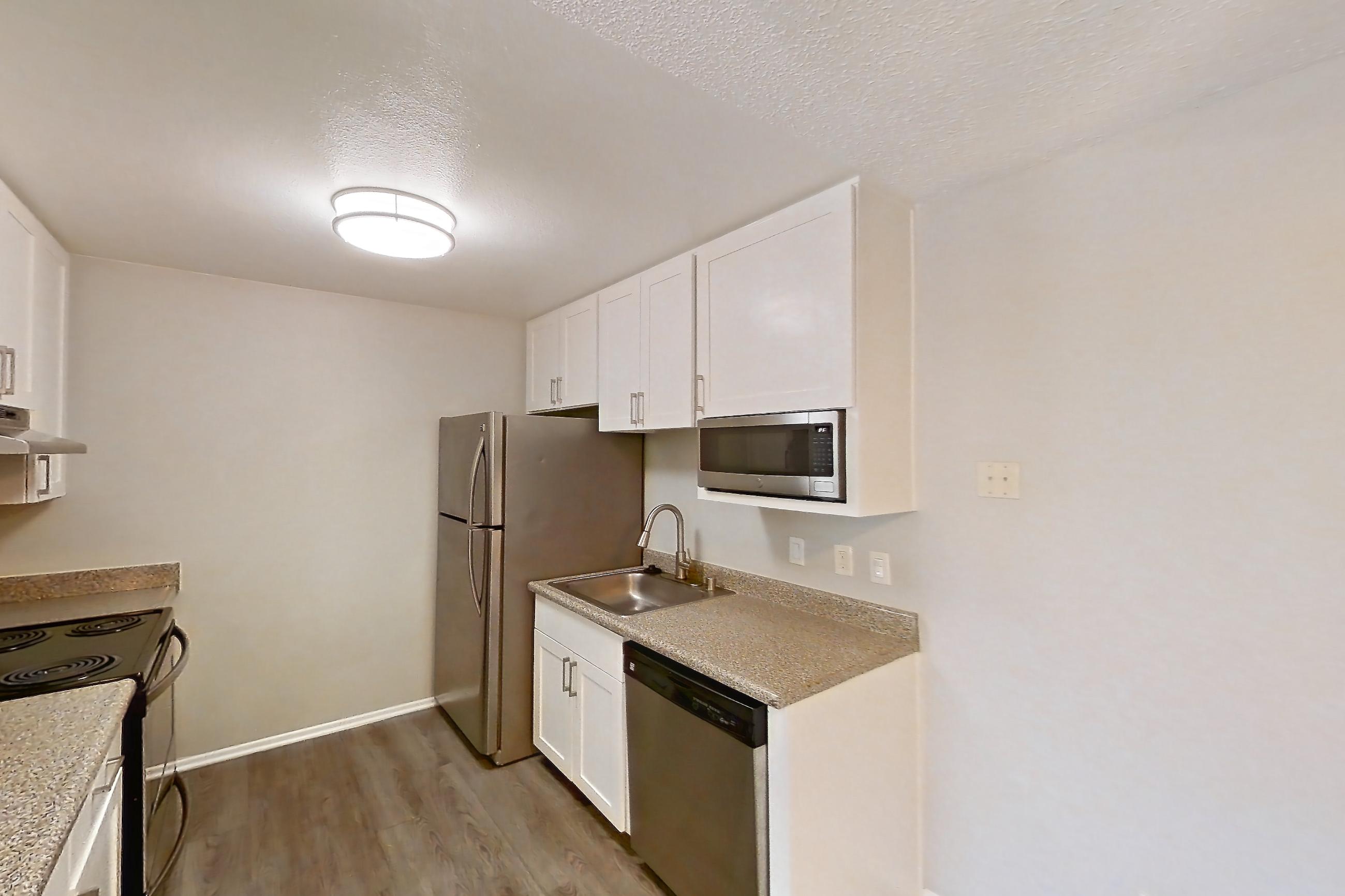 Dining room with black appliances, dark wood-finish flooring, dishwasher, electric range, light carpet, light countertops, light stone countertops, light wood-finish flooring, oven/range, refrigerator, and stainless steel appliances, Apartment 10-04 at Avana Rancho Cucamonga