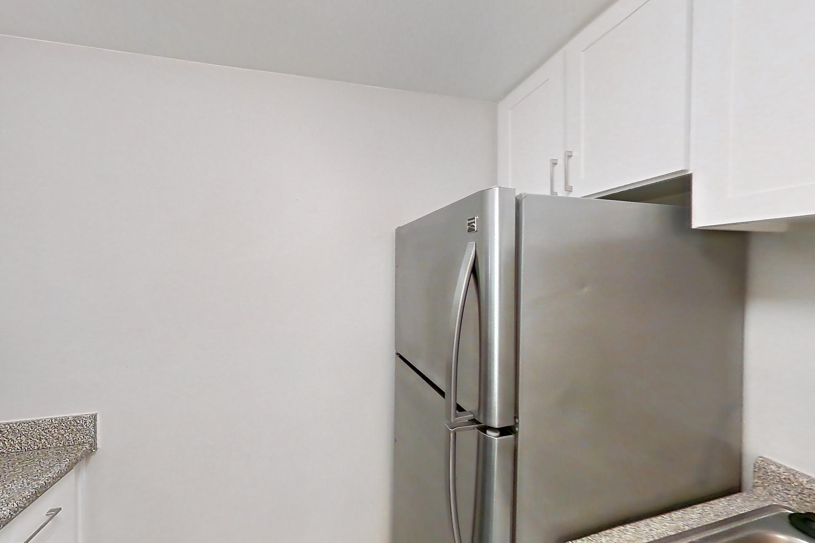 Kitchen with built-in microwave, dishwasher, electric range, light countertops, light stone countertops, light wood-finish flooring, microwave, refrigerator, and stainless steel appliances, Apartment 10-04 at Avana Rancho Cucamonga
