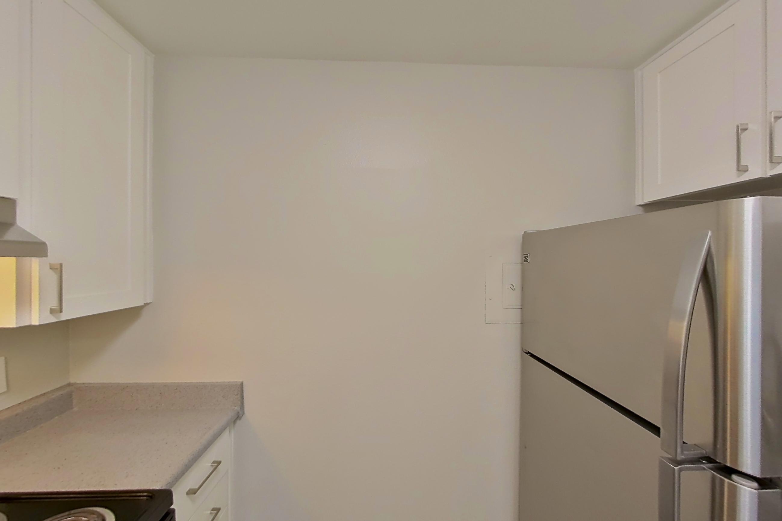 Kitchen with black appliances, dishwasher, electric range, light countertops, light stone countertops, light wood-finish flooring, microwave, oven/range, range hood, refrigerator, stainless steel appliances, and white appliances, Apartment 10-12 at Avana Rancho Cucamonga