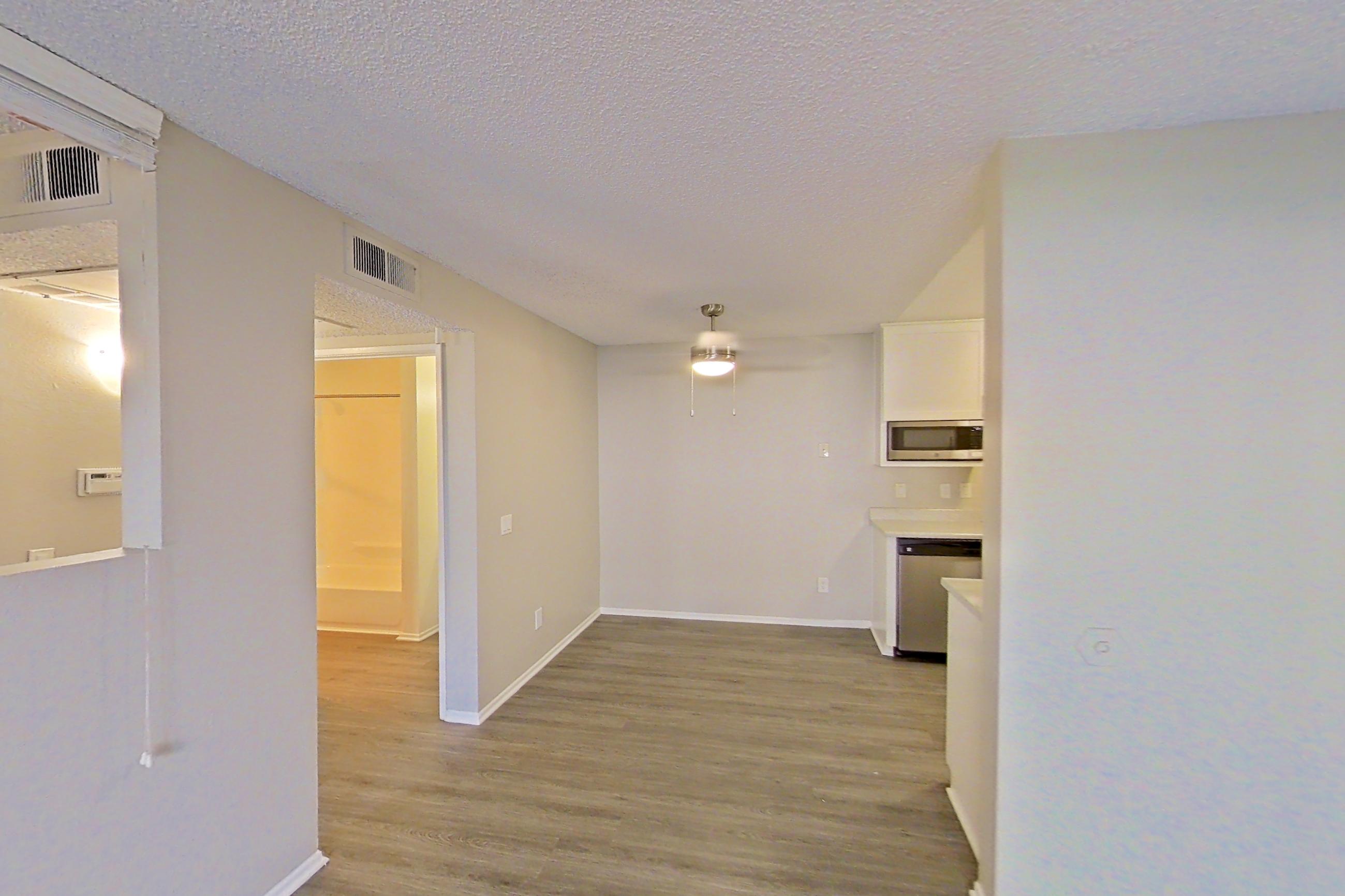 Living room with dark wood-finish flooring, dishwasher, and stainless steel appliances, Apartment 12-06 at Avana Rancho Cucamonga