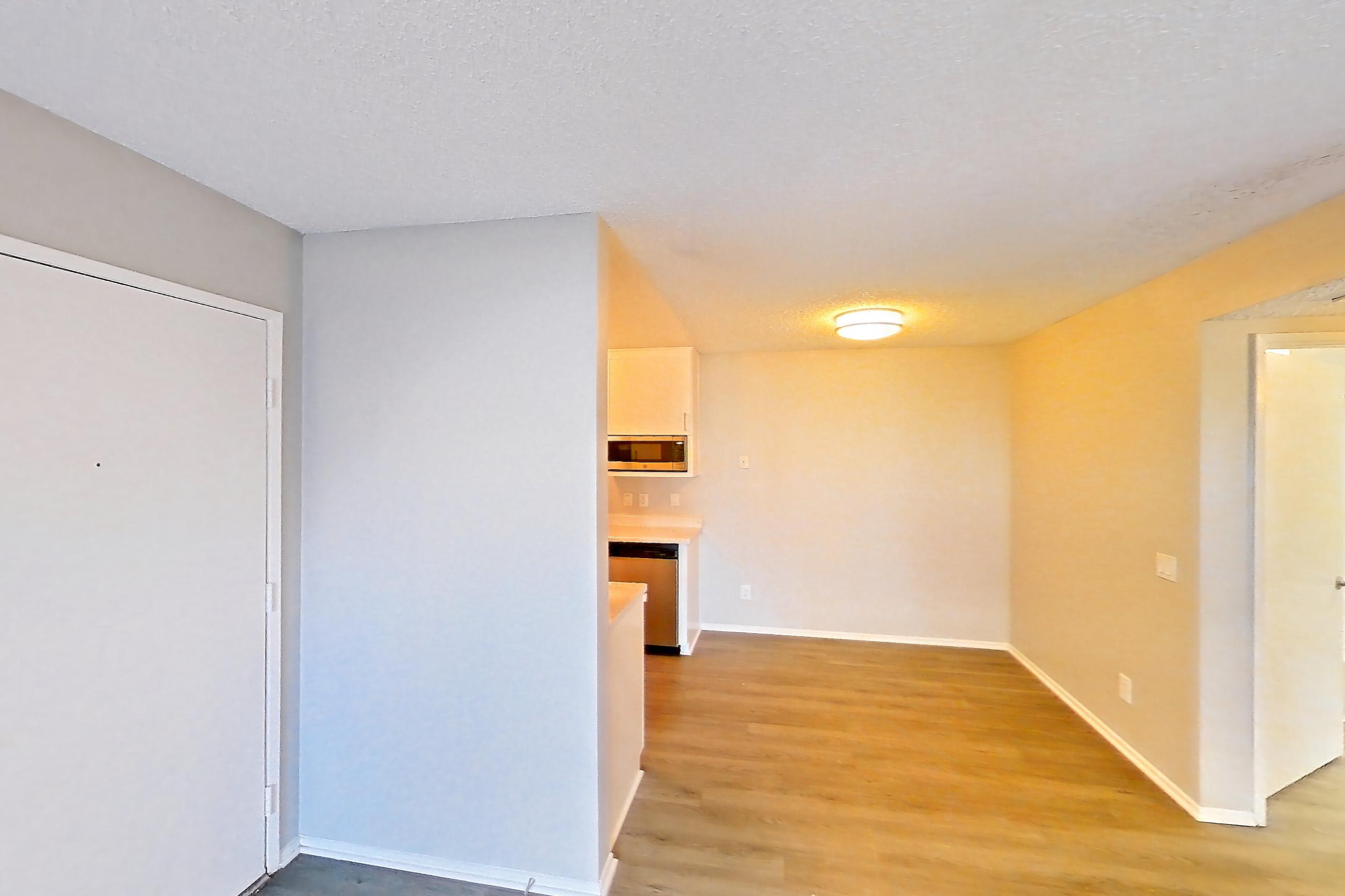 Living room with dark wood-finish flooring, dishwasher, and stainless steel appliances, Apartment 12-08 at Avana Rancho Cucamonga