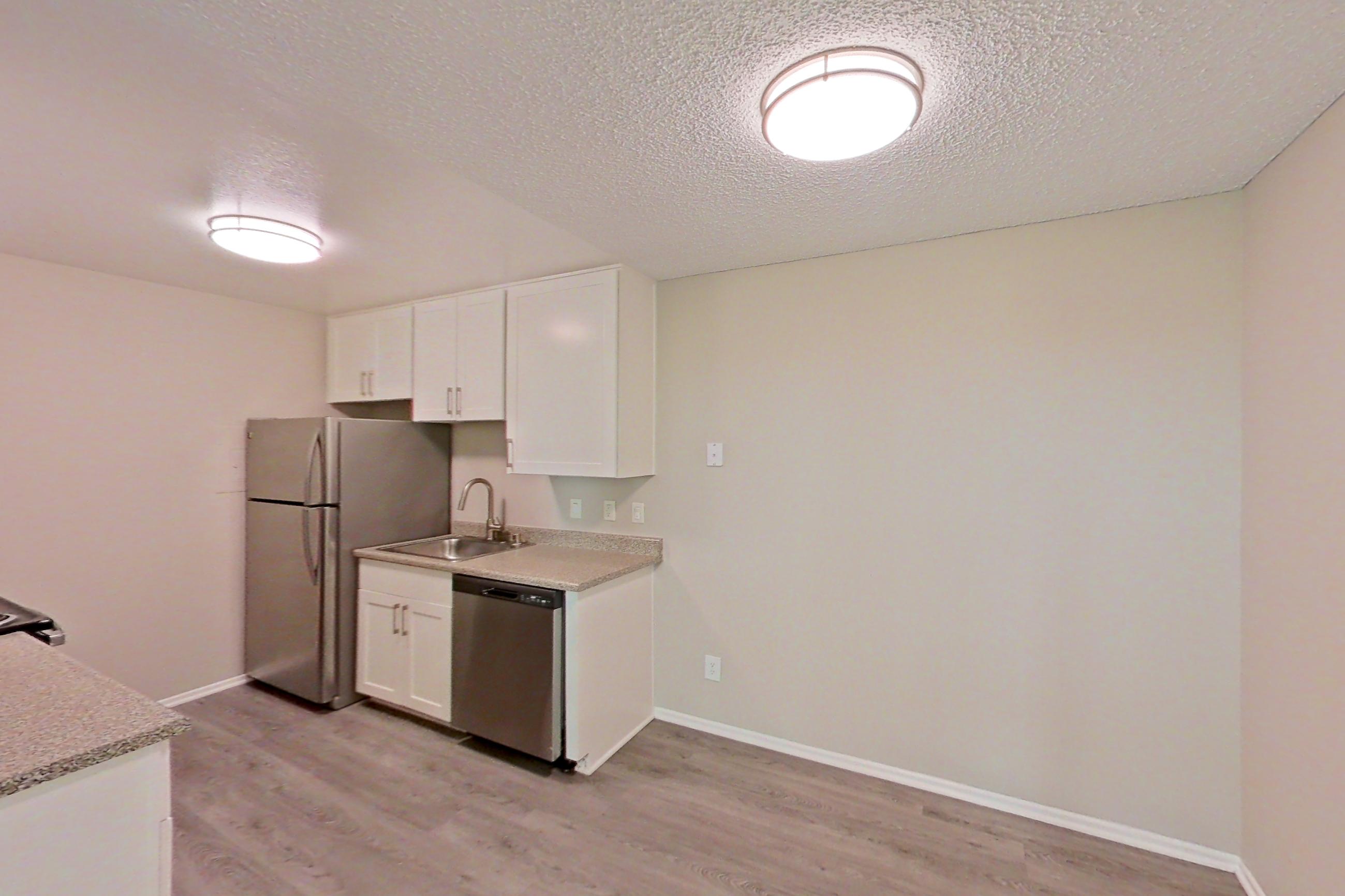 Dining area with dishwasher, light stone countertops, light wood-finish flooring, refrigerator, and stainless steel appliances, Apartment 13-04 at Avana Rancho Cucamonga