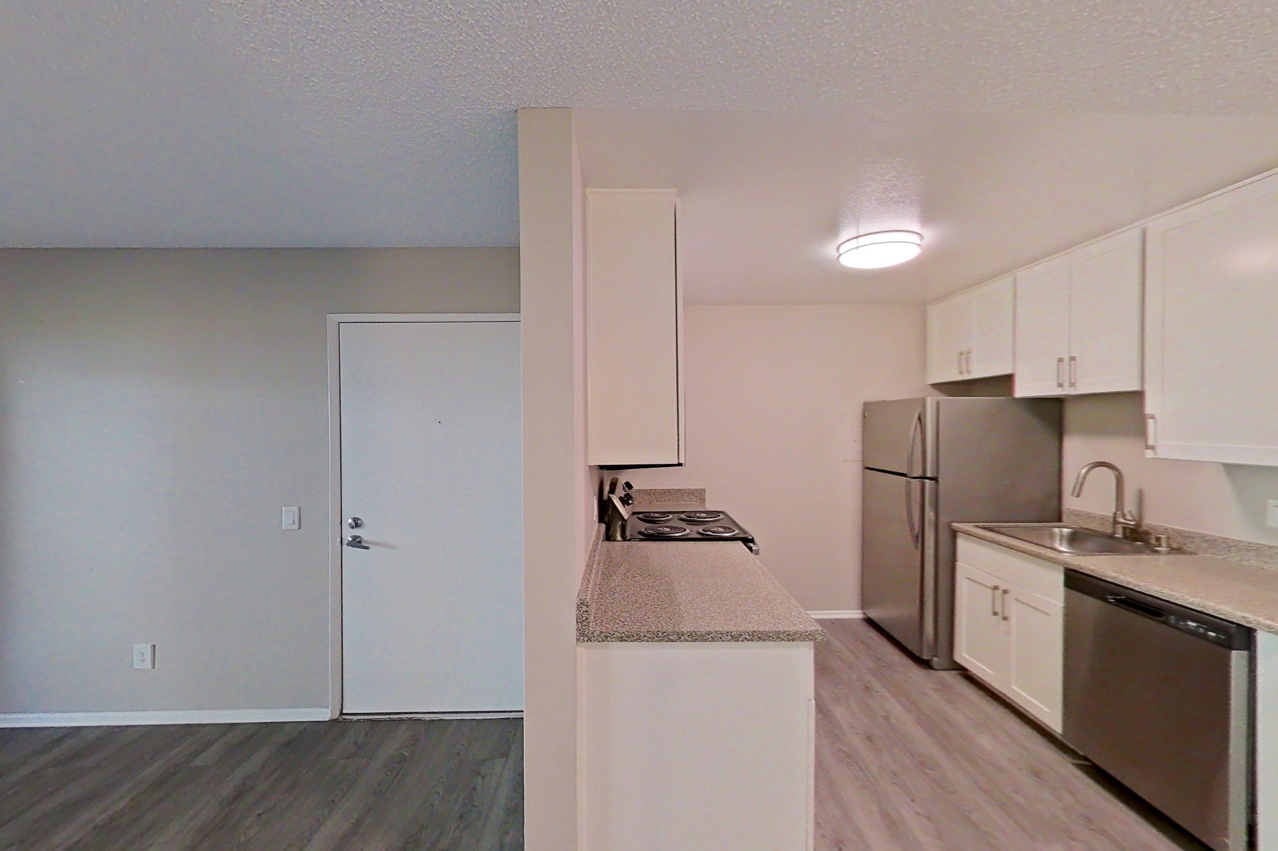 Dining area with dishwasher, light stone countertops, light wood-finish flooring, refrigerator, and stainless steel appliances, Apartment 13-04 at Avana Rancho Cucamonga