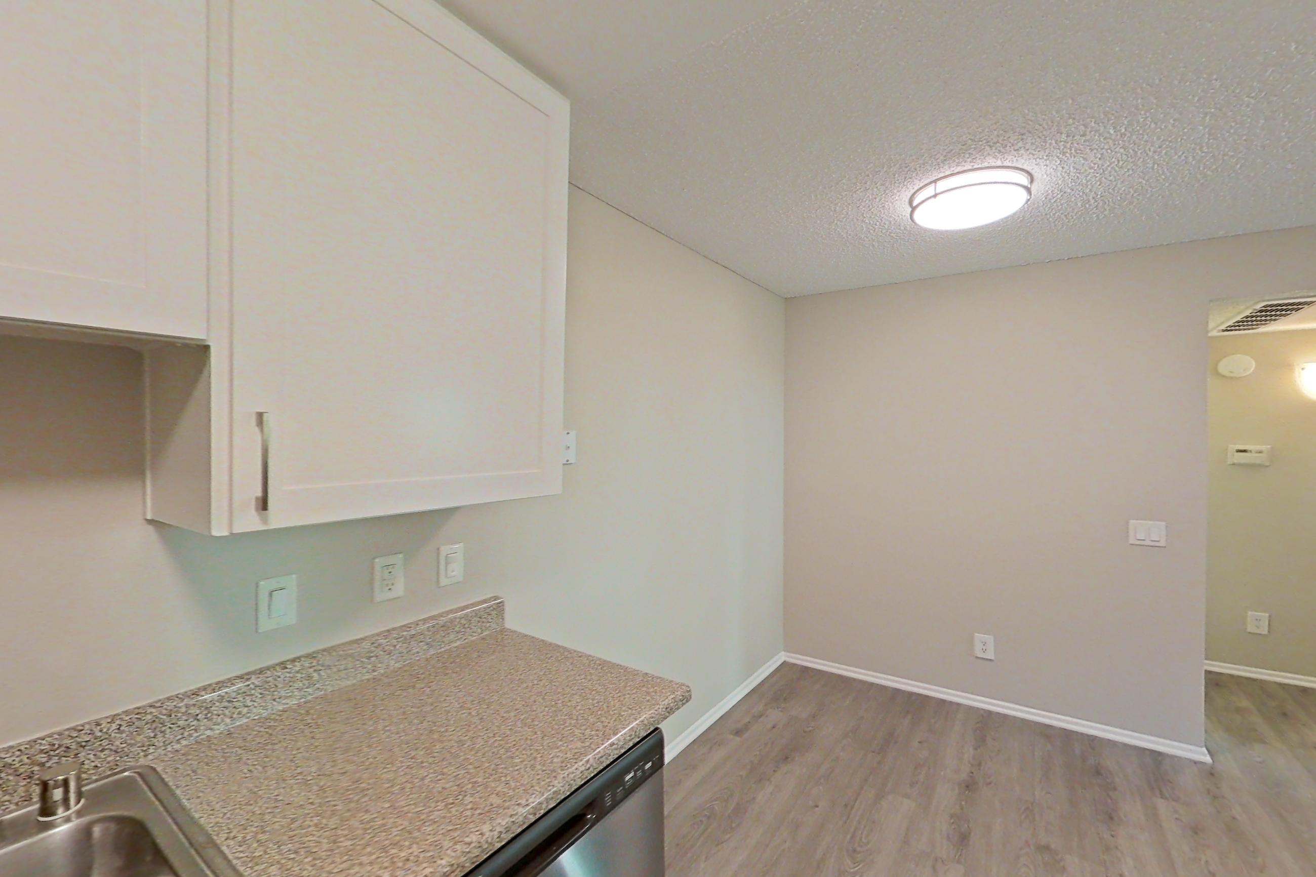 Kitchen with dishwasher, electric range, light countertops, light stone countertops, light wood-finish flooring, microwave, oven/range, and stainless steel appliances, Apartment 13-04 at Avana Rancho Cucamonga