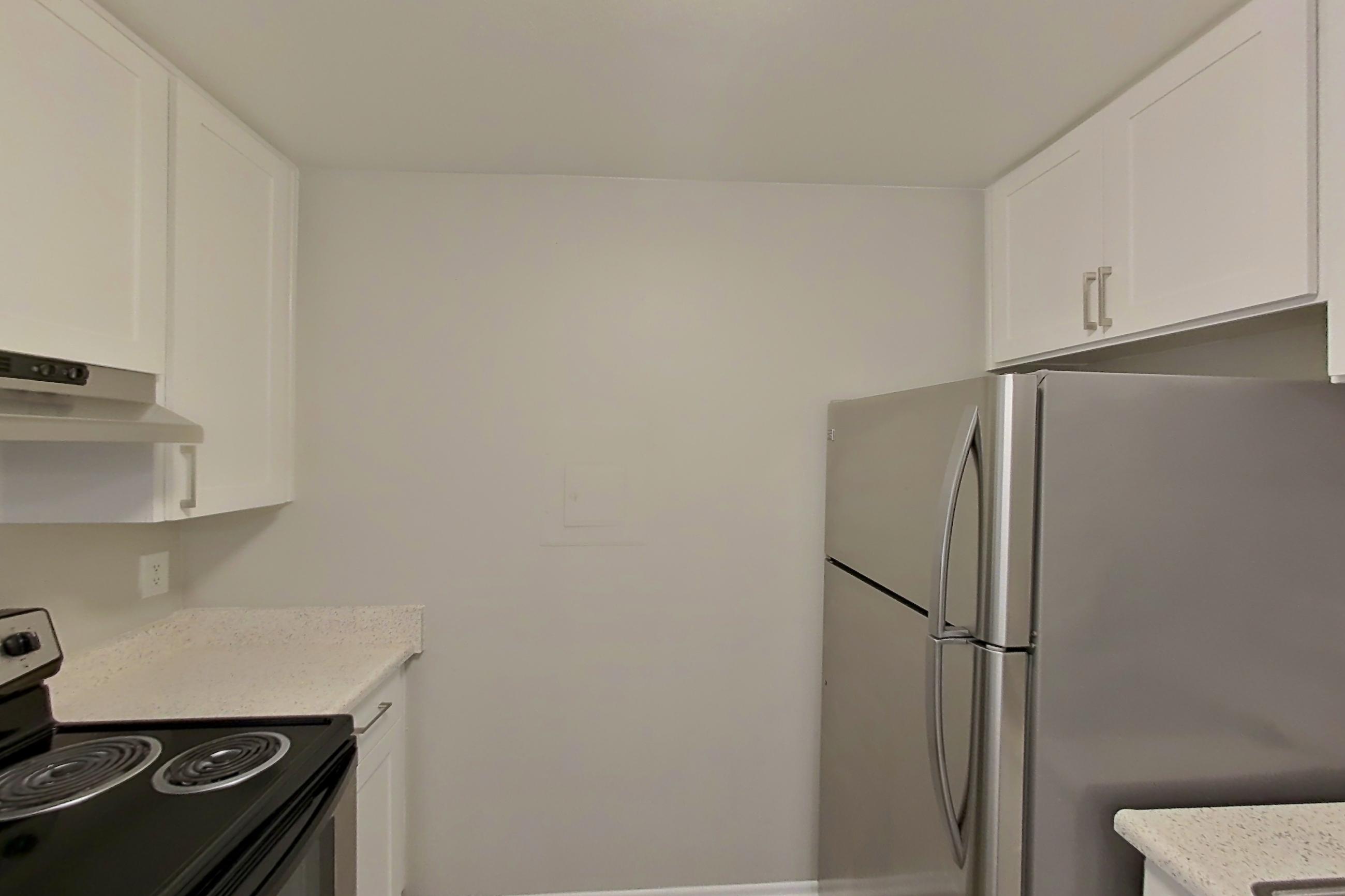 Kitchen with dishwasher, electric range, light countertops, light stone countertops, light wood-finish flooring, microwave, oven/range, refrigerator, stainless steel appliances, and white appliances, Apartment 14-02 at Avana Rancho Cucamonga