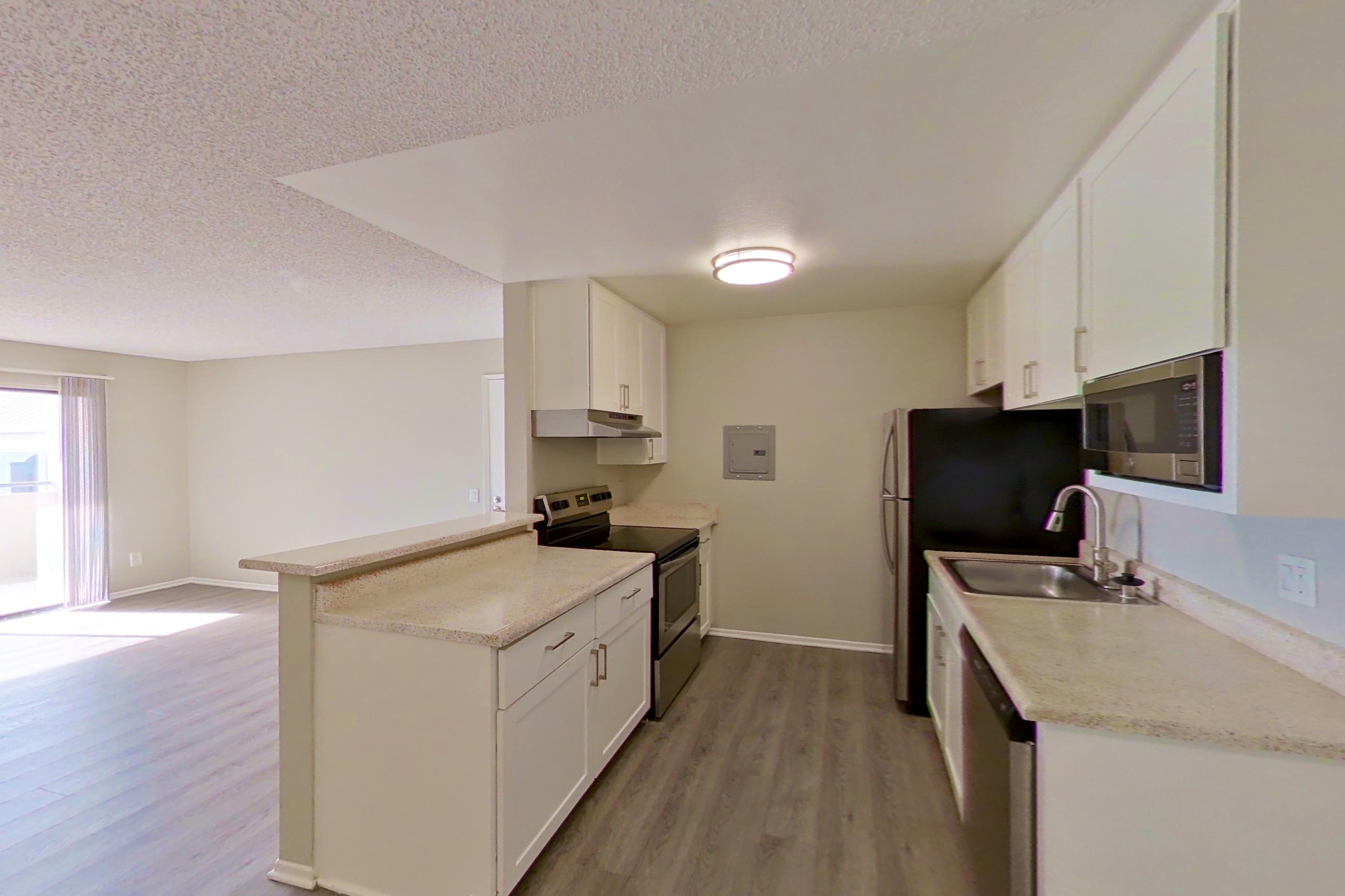 Dining space with dishwasher, electric range, in-unit laundry, light countertops, light wood-finish flooring, oven/range, and stainless steel appliances, Apartment 15-06 at Avana Rancho Cucamonga