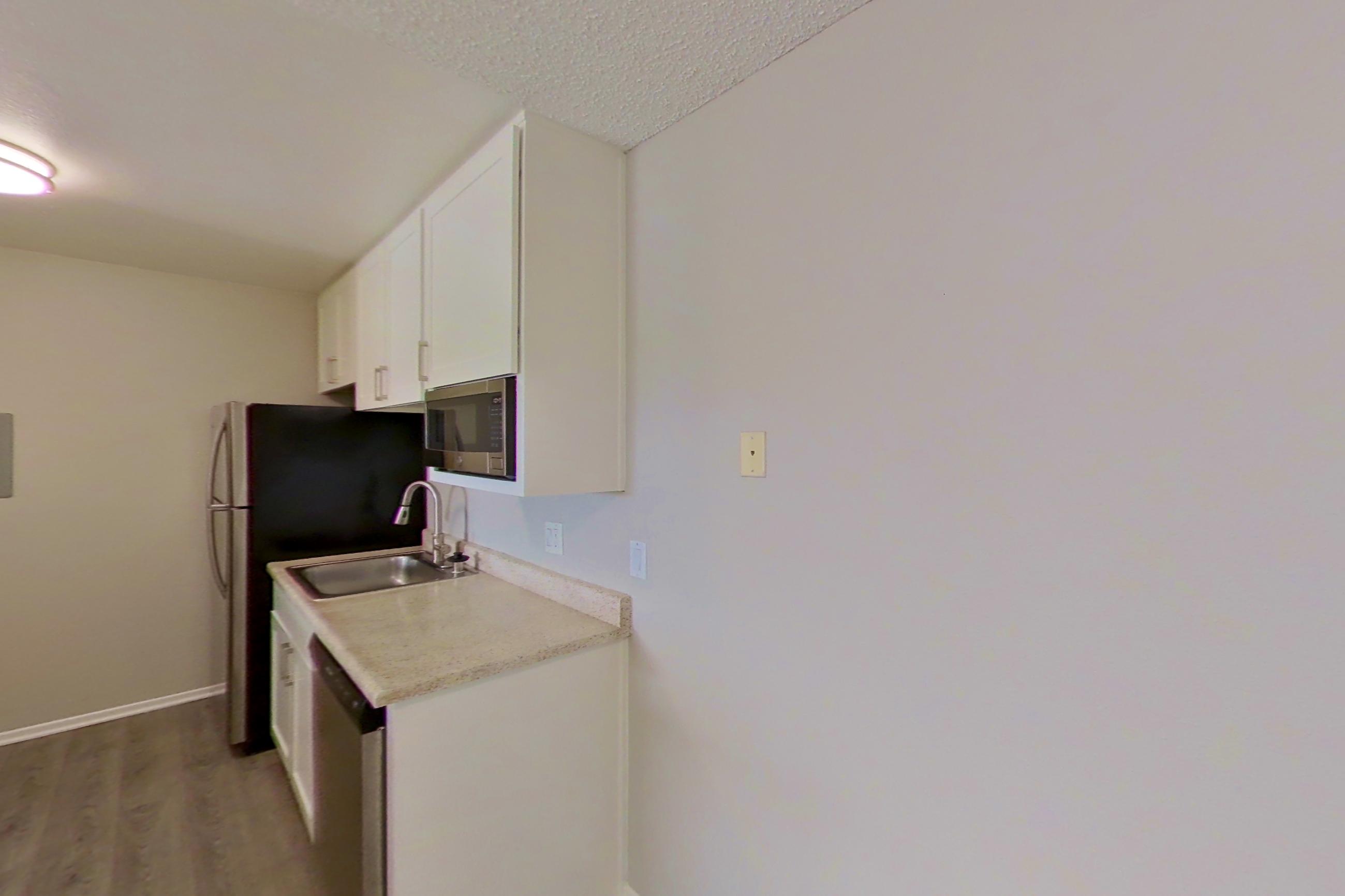 Dining space with dishwasher, electric range, in-unit laundry, light countertops, light wood-finish flooring, oven/range, and stainless steel appliances, Apartment 15-06 at Avana Rancho Cucamonga