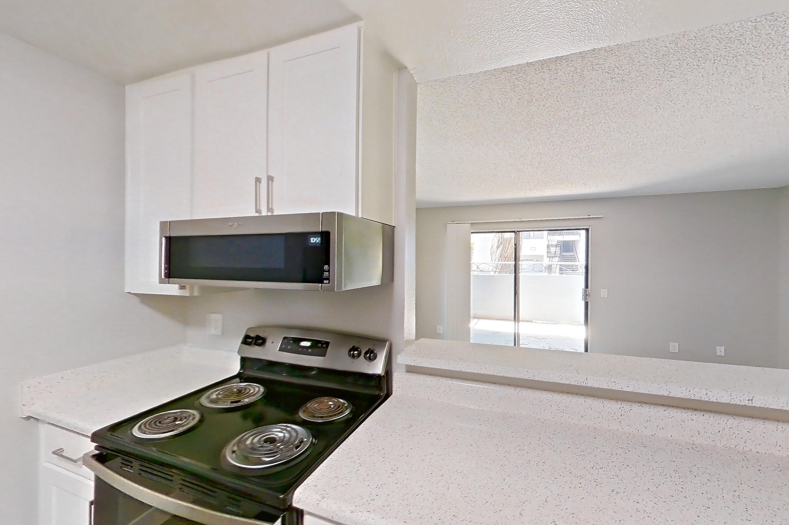 Kitchen with dishwasher, electric range, light countertops, light stone countertops, light wood-finish flooring, oven/range, and stainless steel appliances, Apartment 16-01 at Avana Rancho Cucamonga
