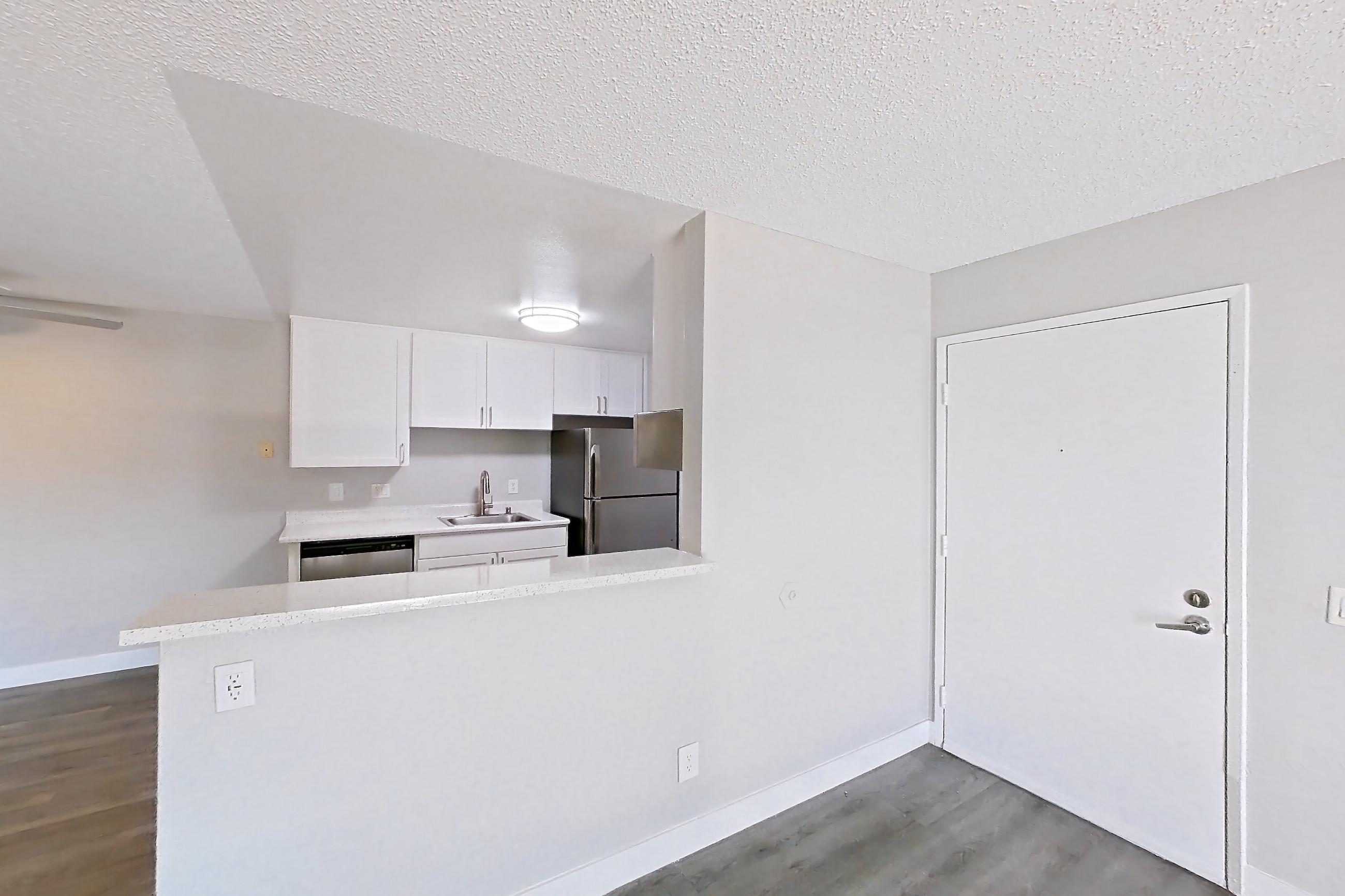 Living room with dark wood-finish flooring, dishwasher, light wood-finish flooring, refrigerator, and stainless steel appliances, Apartment 16-01 at Avana Rancho Cucamonga