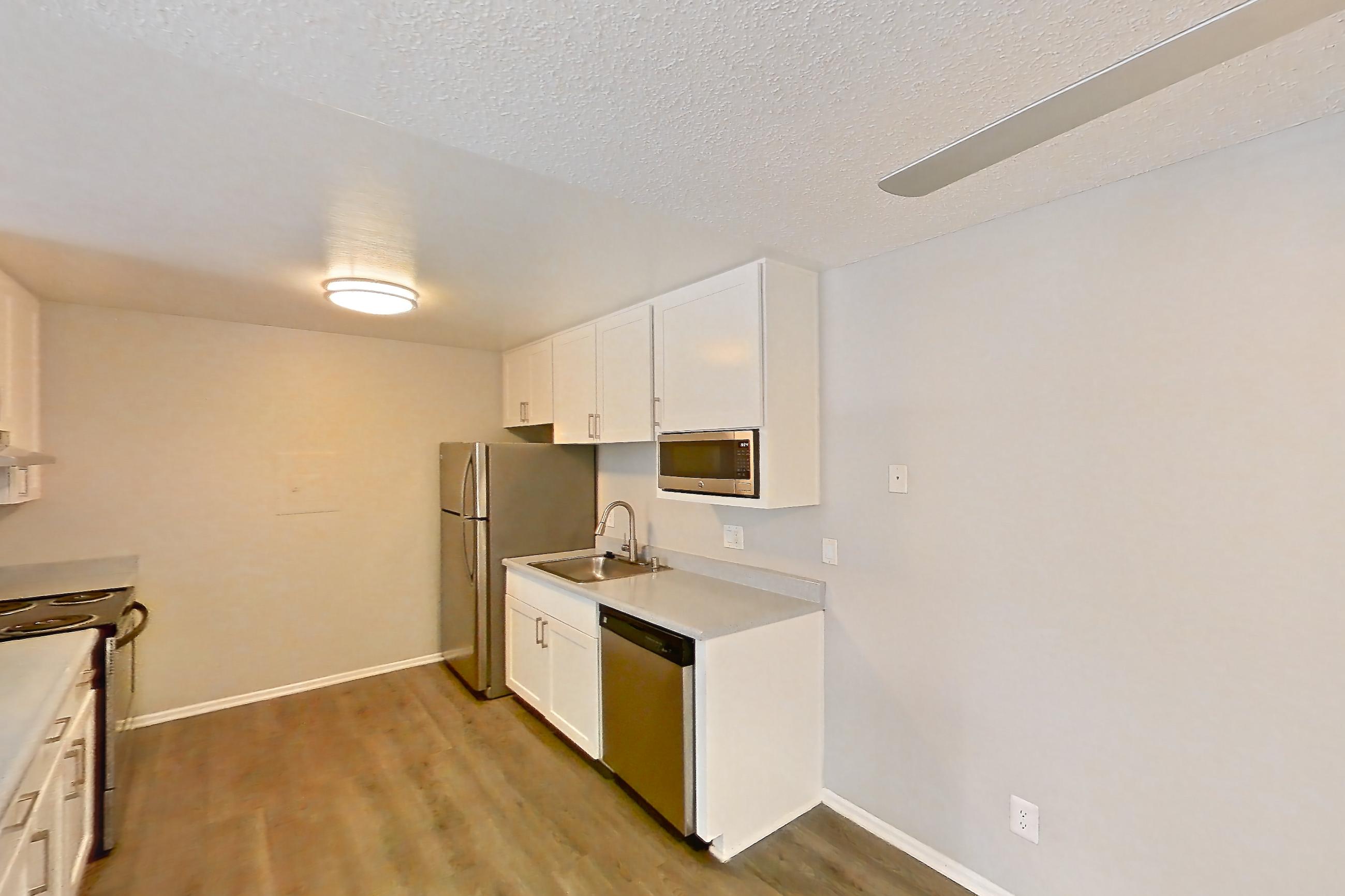 Dining room with black appliances, dark carpet, dark wood-finish flooring, dishwasher, electric range, light countertops, light wood-finish flooring, oven/range, refrigerator, and stainless steel appliances, Apartment 16-03 at Avana Rancho Cucamonga