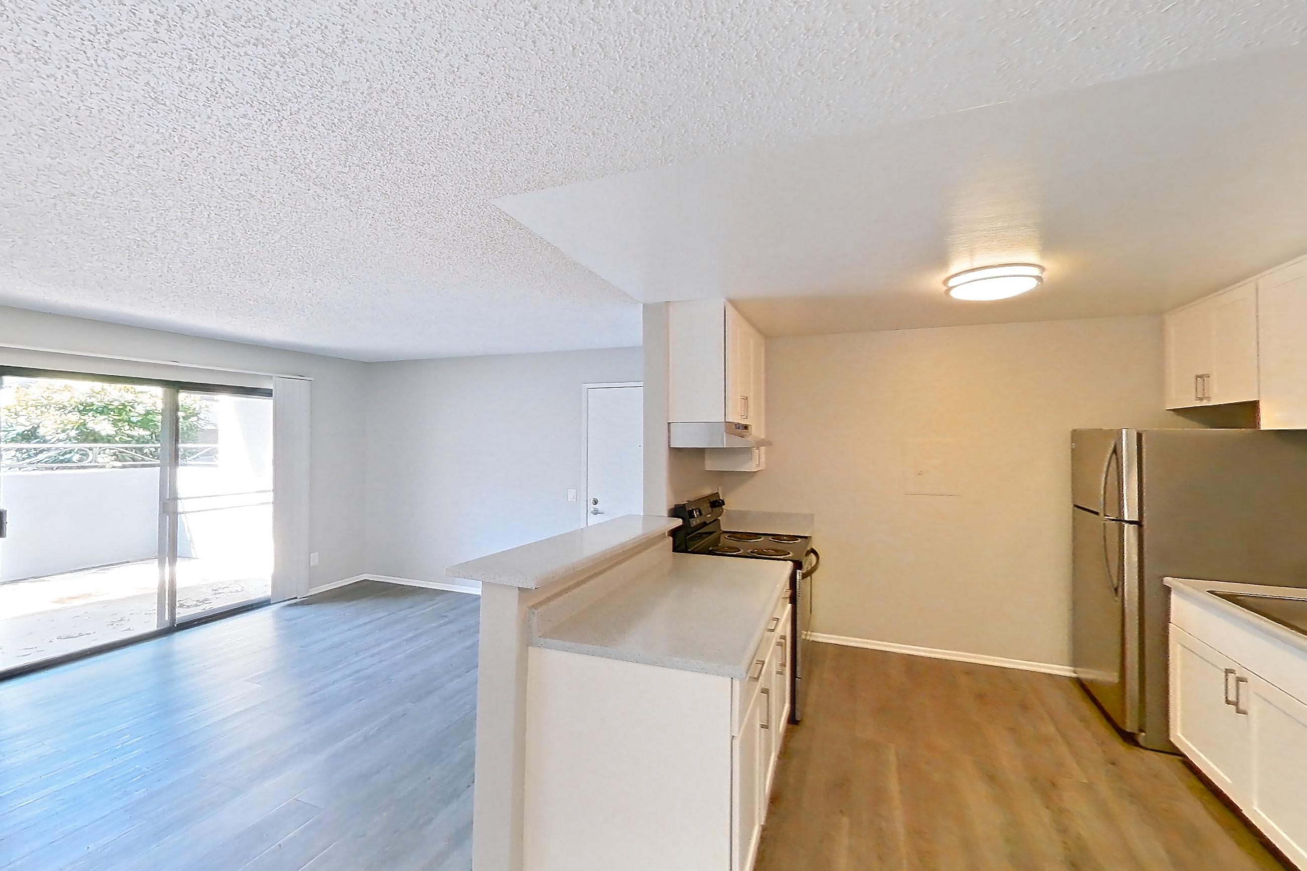 Dining room with black appliances, dark carpet, dark wood-finish flooring, dishwasher, electric range, light countertops, light wood-finish flooring, oven/range, refrigerator, and stainless steel appliances, Apartment 16-03 at Avana Rancho Cucamonga
