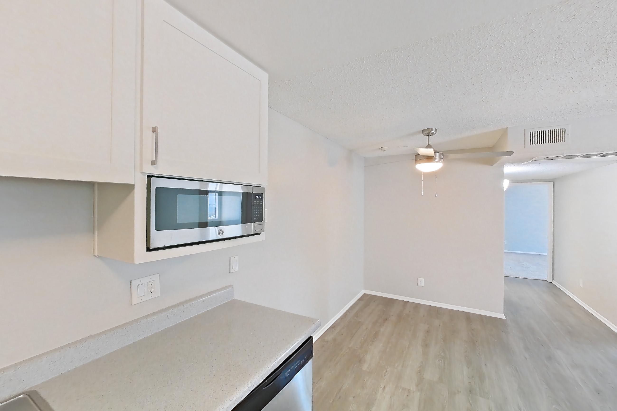 Kitchen with dishwasher, electric range, light countertops, light wood-finish flooring, microwave, oven/range, refrigerator, and stainless steel appliances, Apartment 16-03 at Avana Rancho Cucamonga