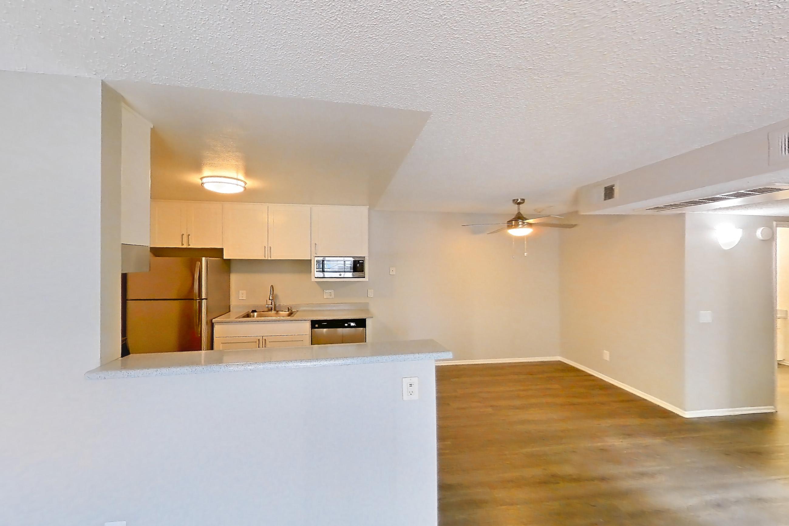 Living room with dark wood-finish flooring, dishwasher, refrigerator, and stainless steel appliances, Apartment 16-03 at Avana Rancho Cucamonga